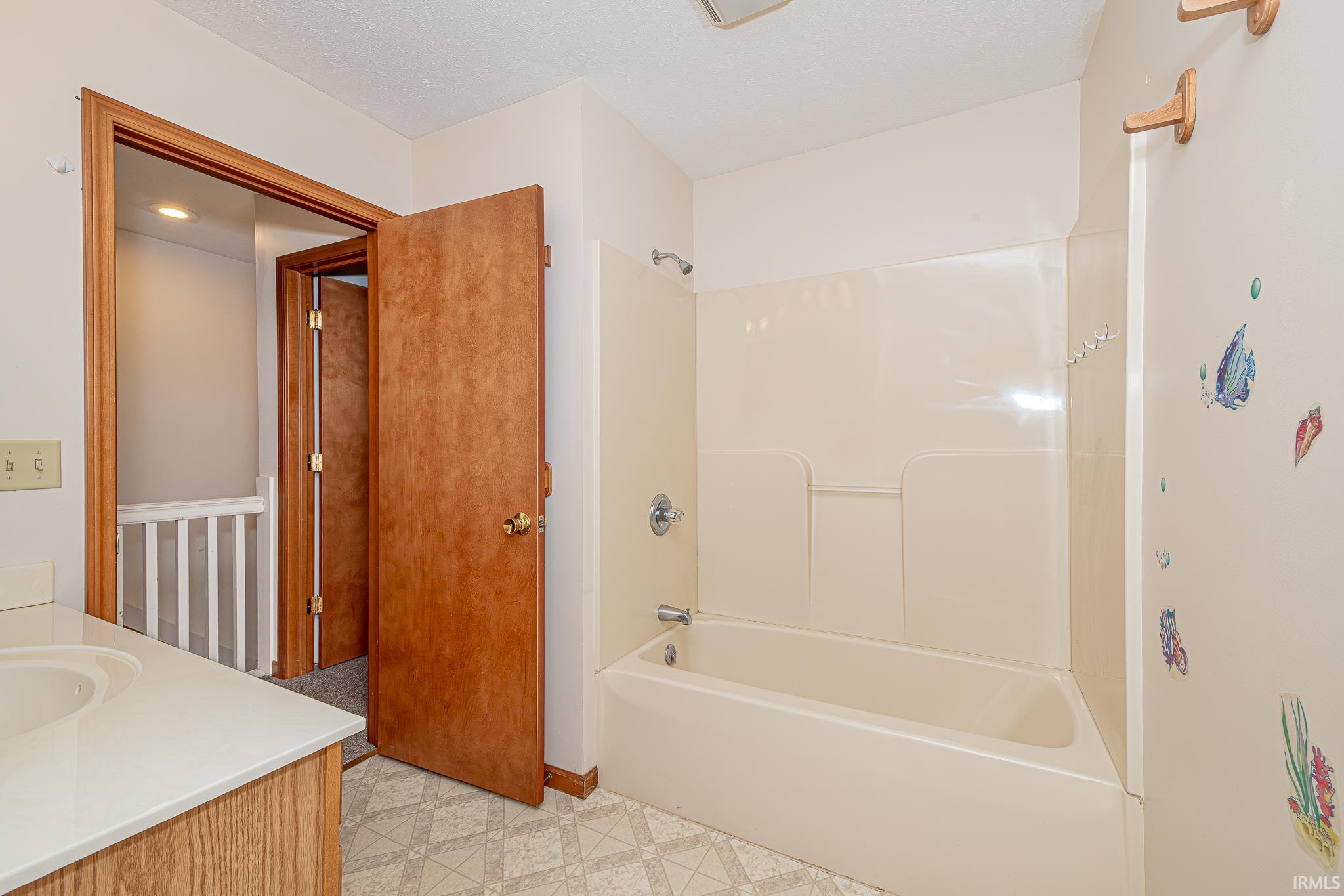 Bathroom with vanity, shower / washtub combination, and light flooring