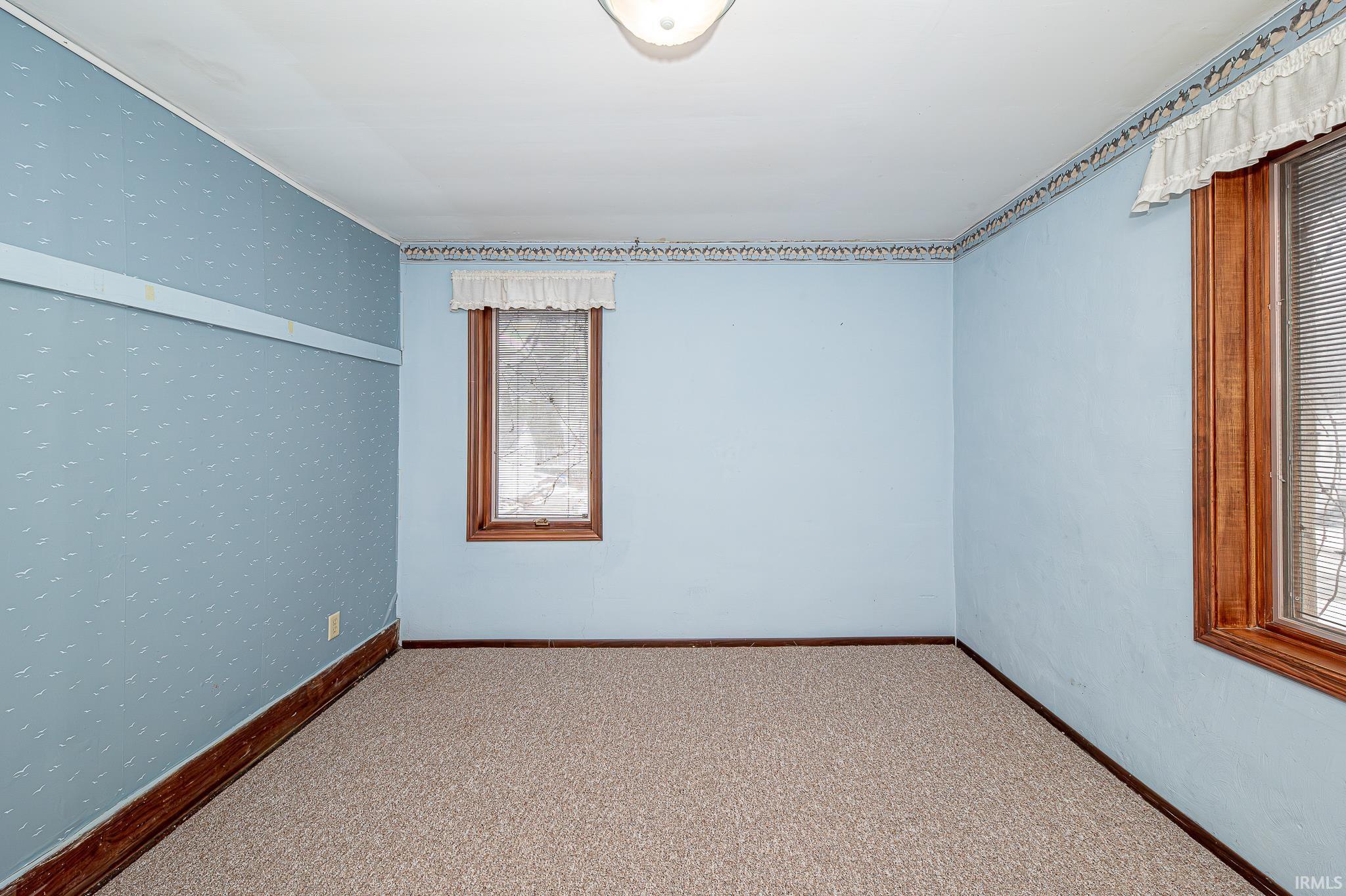 Carpeted empty room with wallpapered walls and baseboards