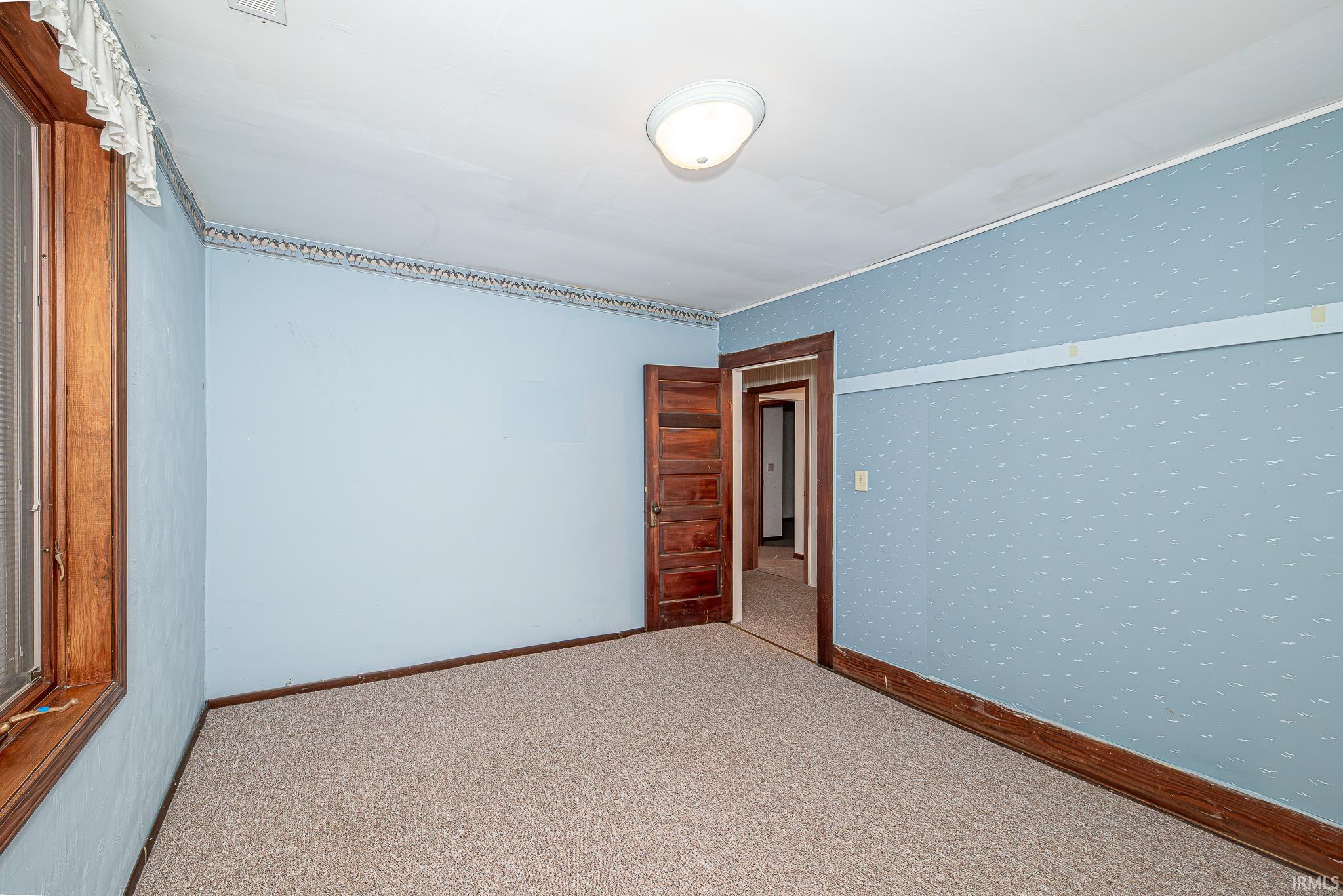 Carpeted spare room featuring wallpapered walls and baseboards