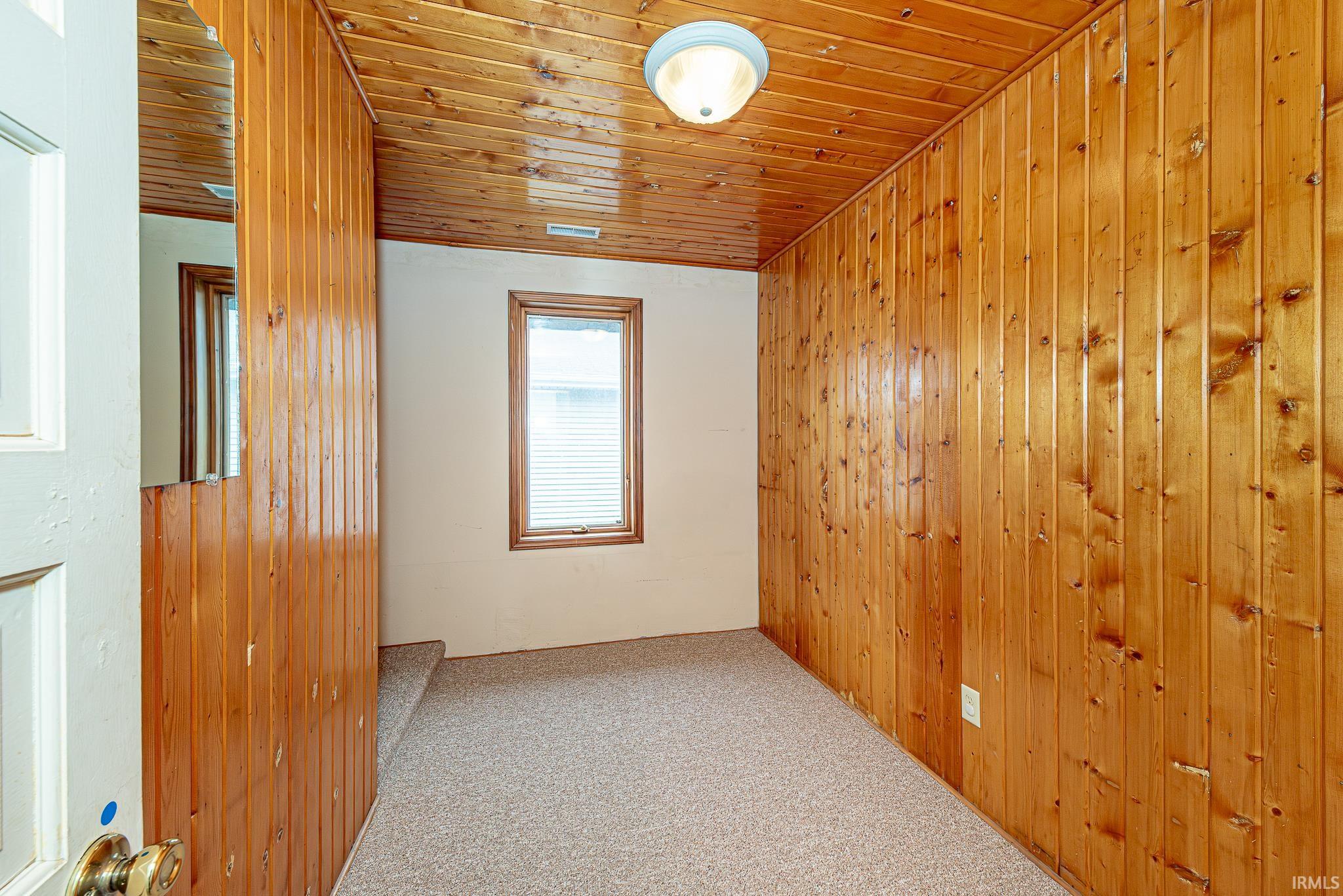 Empty room featuring wood walls, wood ceiling, and carpet floors