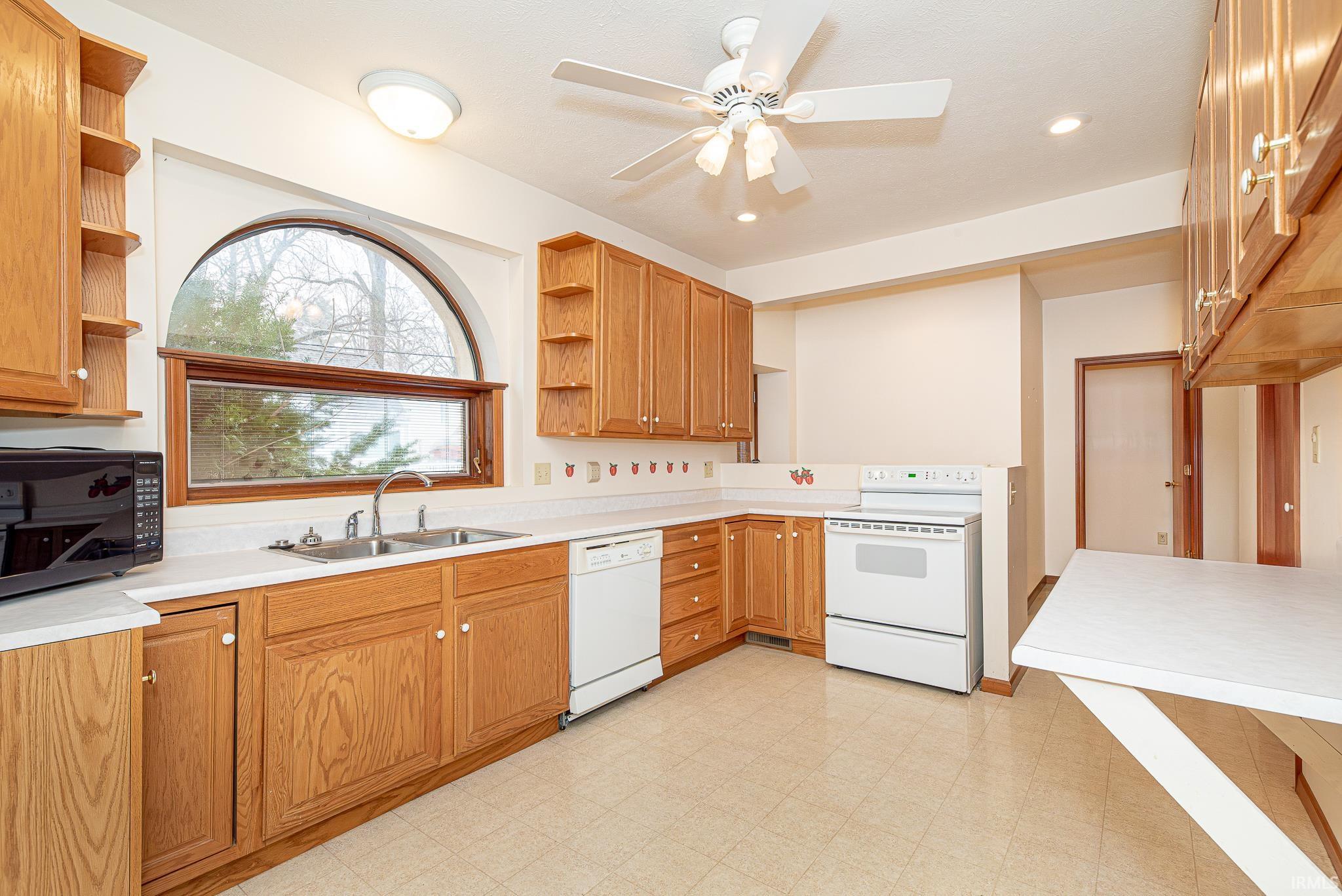 Kitchen with open shelves, white appliances, light countertops, light flooring, and recessed lighting