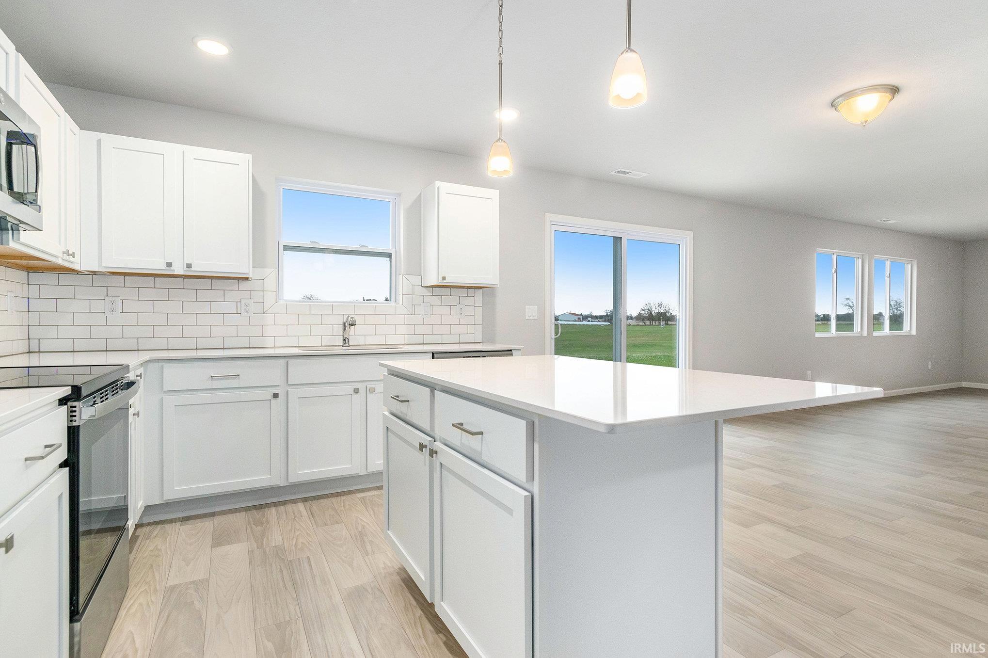 The kitchen includes a center island for additional storage & prep space. The extended edge can fit barstools and there is pendant lighting above. Quartz counters accented by subway tile backsplash and full stainless steel appliances and fridge included.
