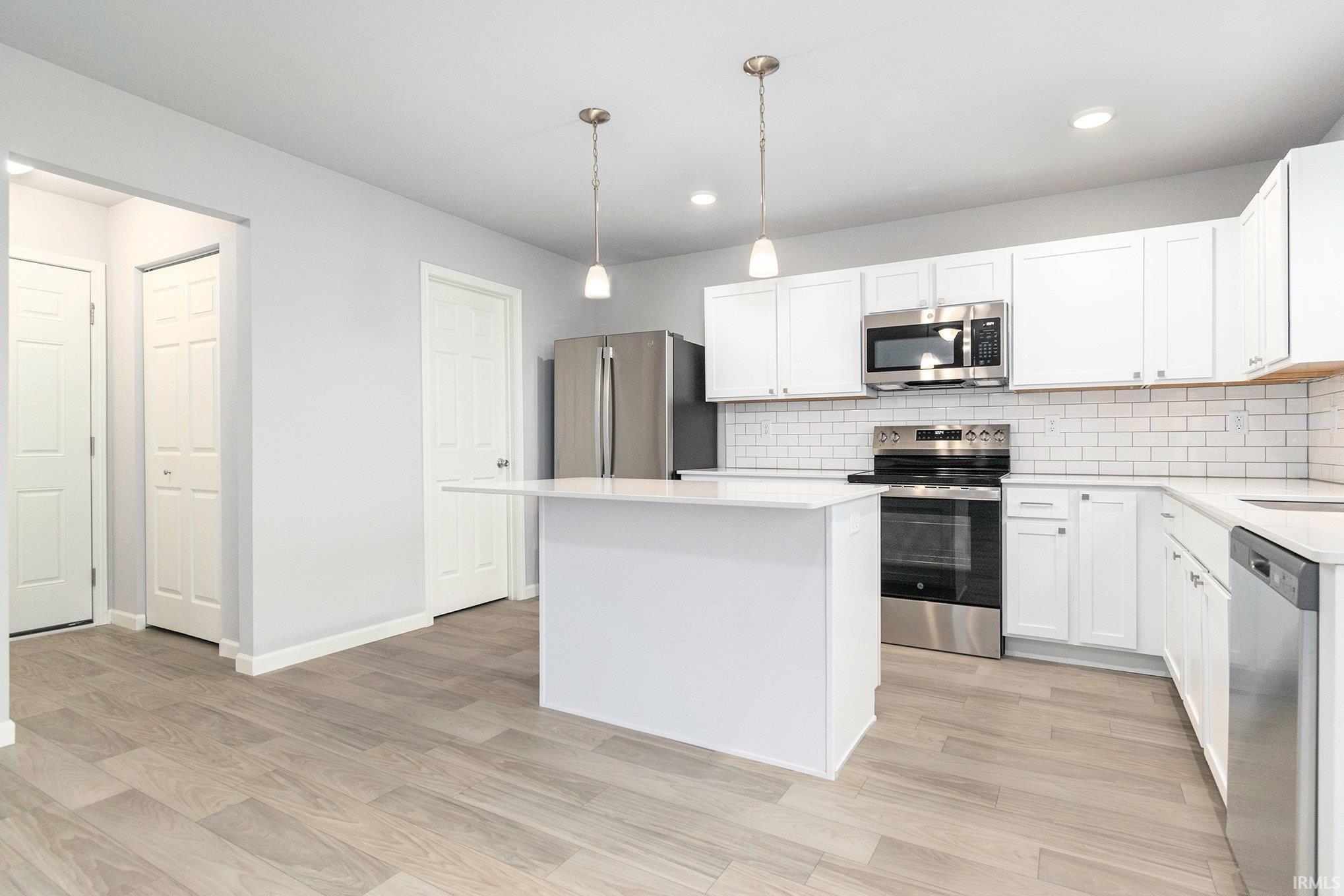 The kitchen includes a center island for additional storage & prep space. The extended edge can fit barstools and there is pendant lighting above. Quartz counters accented by subway tile backsplash and full stainless steel appliances and fridge included.