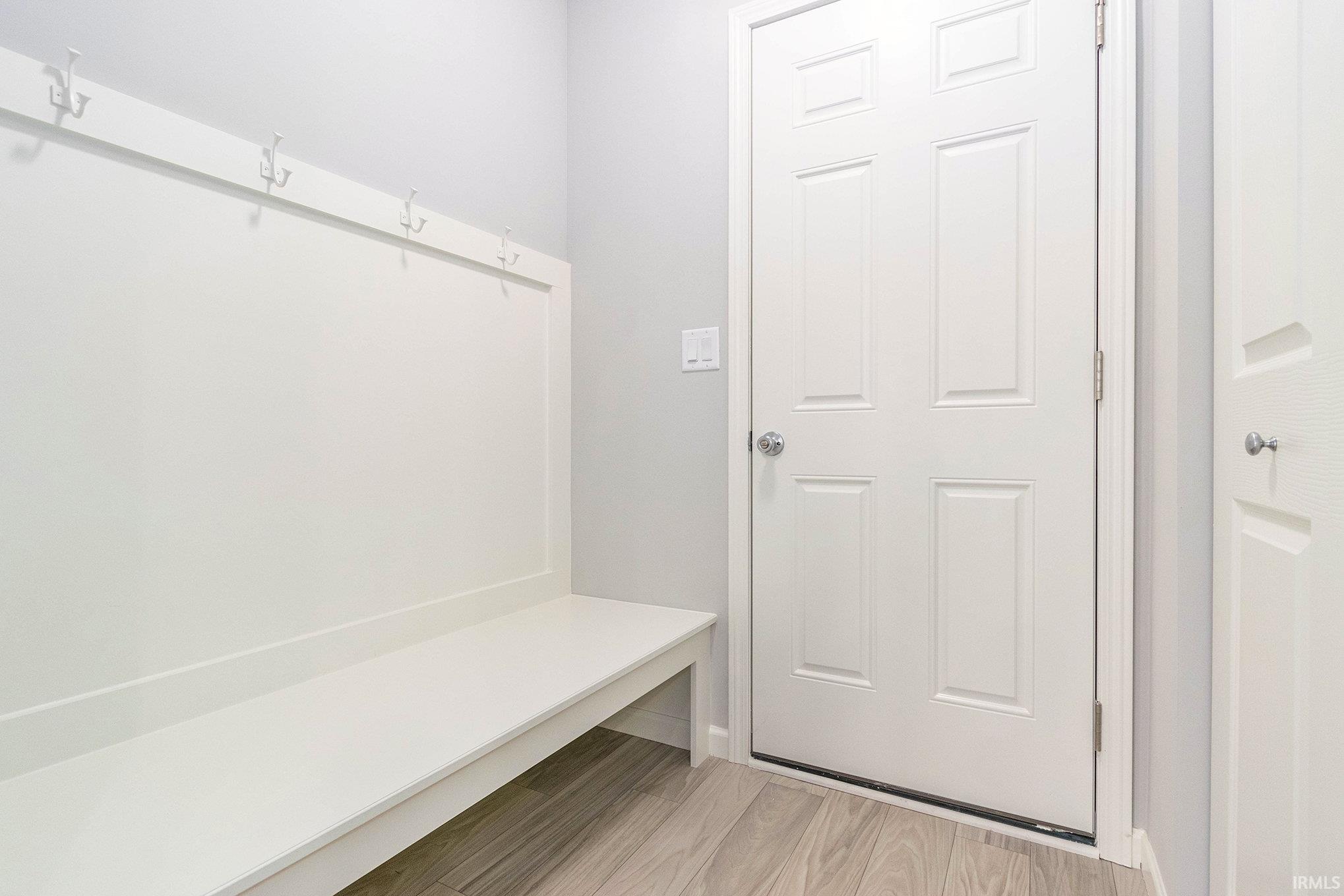 The mudroom has a built-in bench for storage and has access to the garage.
