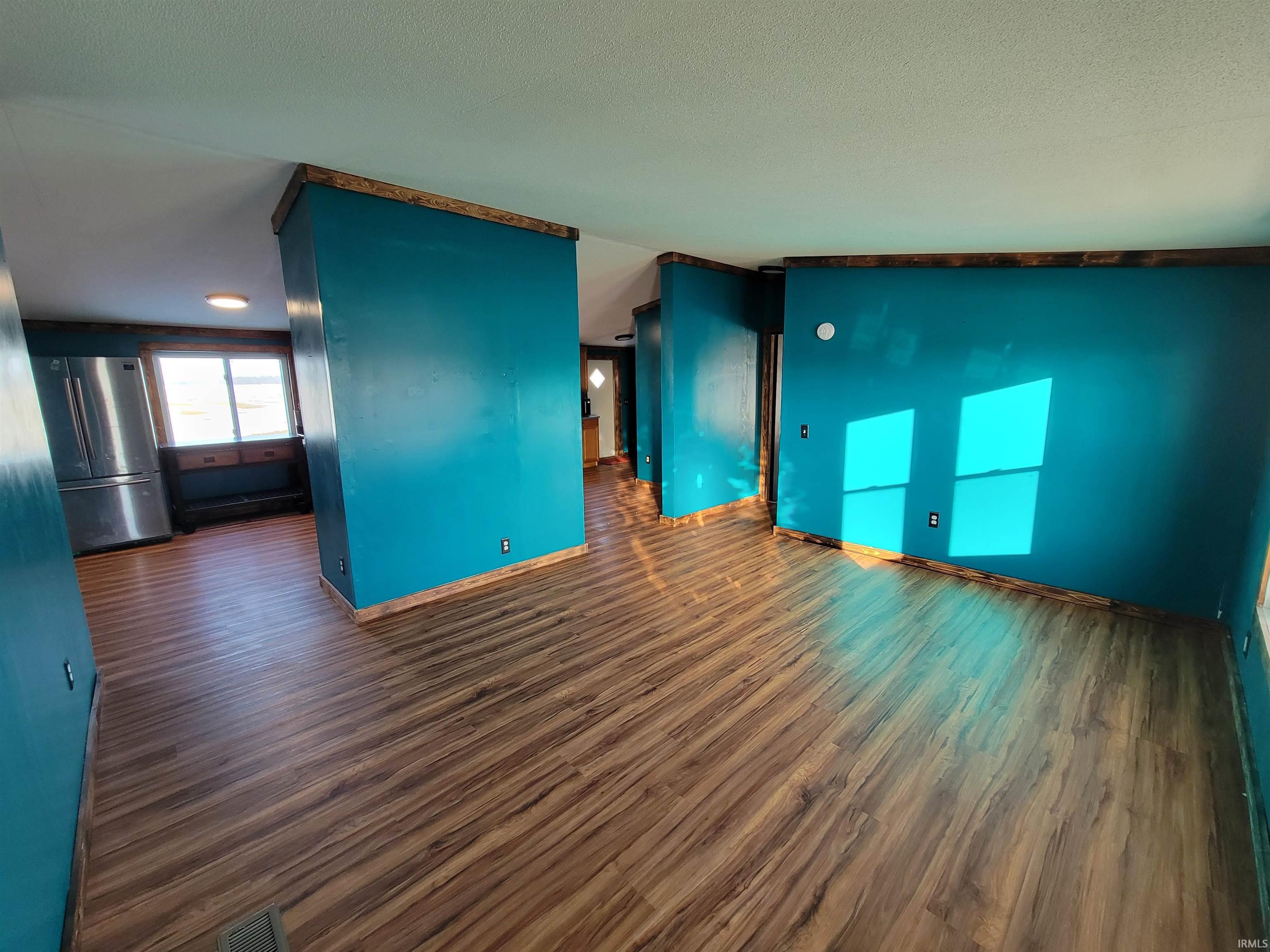 Empty room featuring dark wood-type flooring and a textured ceiling