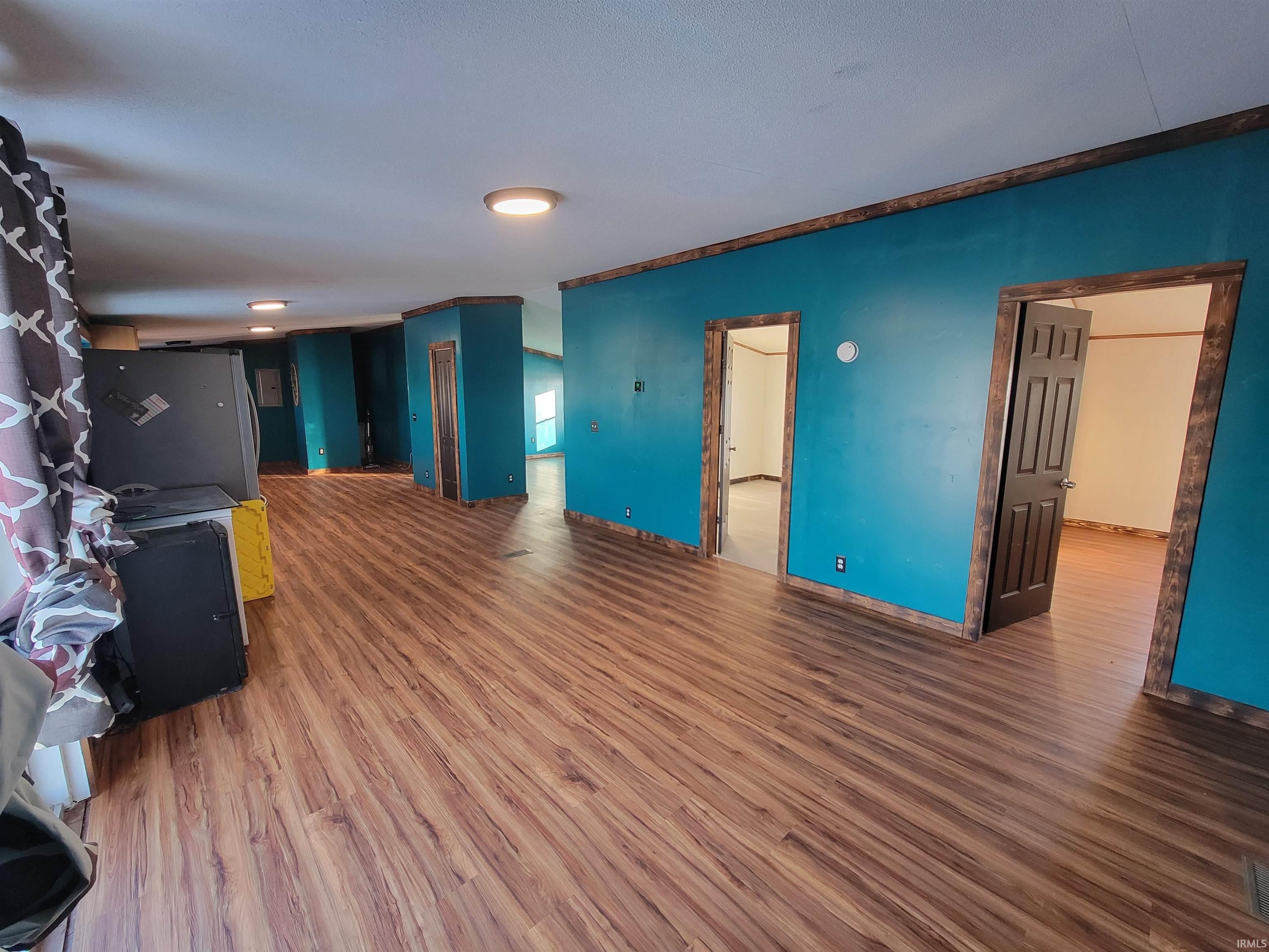 Unfurnished living room featuring wood finished floors and baseboards