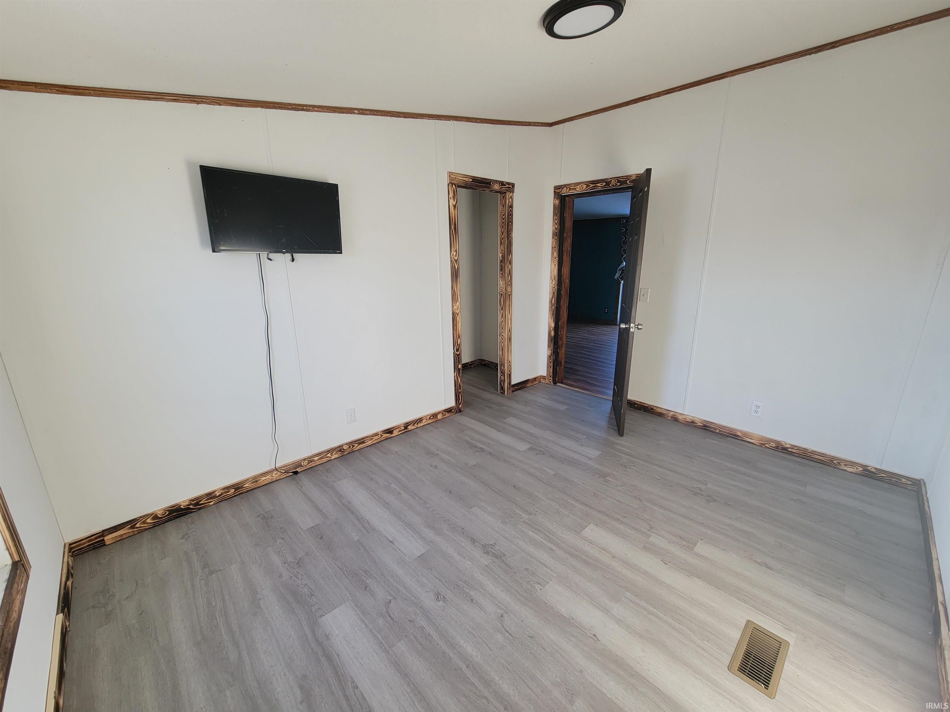 Unfurnished room featuring light wood-type flooring and ornamental molding