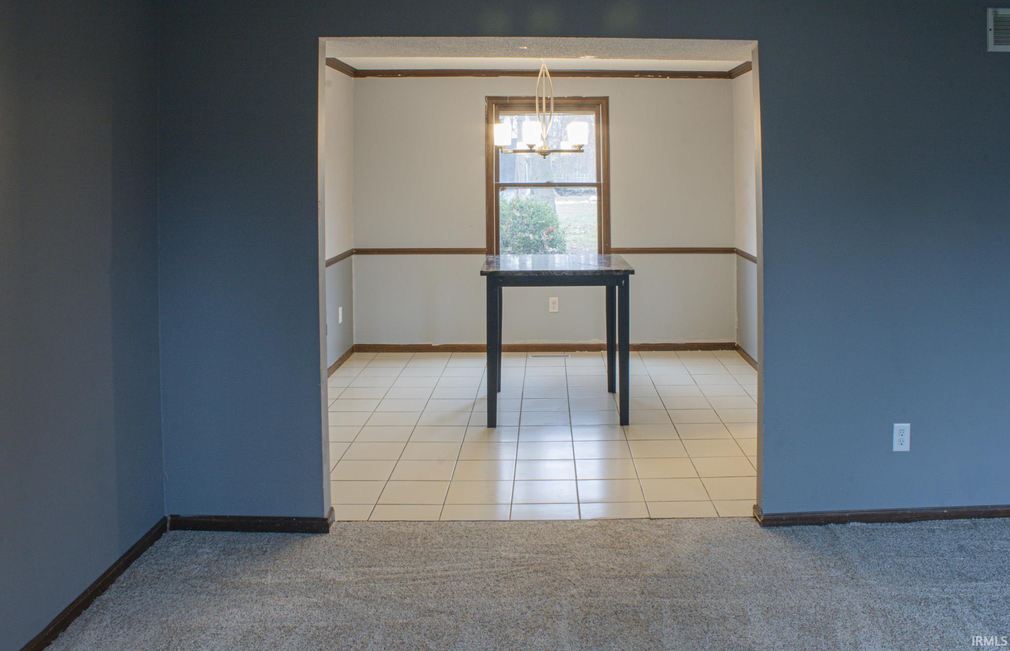 Unfurnished dining area with light tile patterned flooring, light colored carpet, and a chandelier