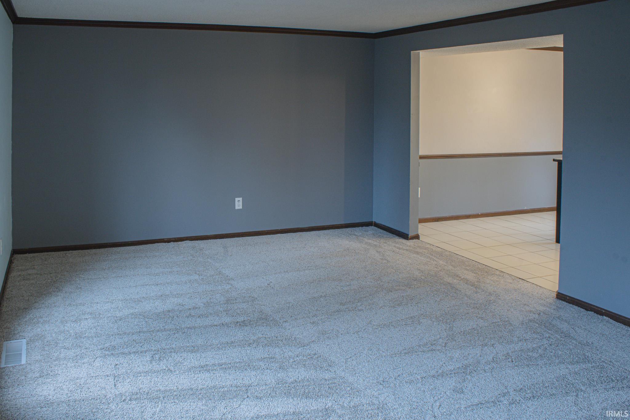 Empty room with light colored carpet and crown molding
