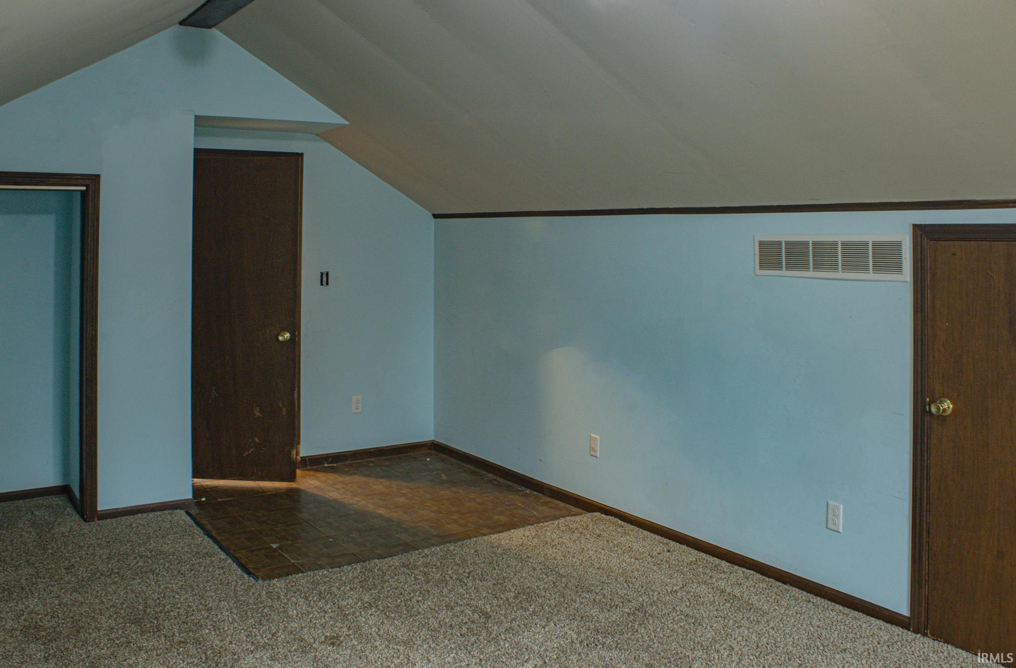 Additional living space featuring lofted ceiling and dark colored carpet