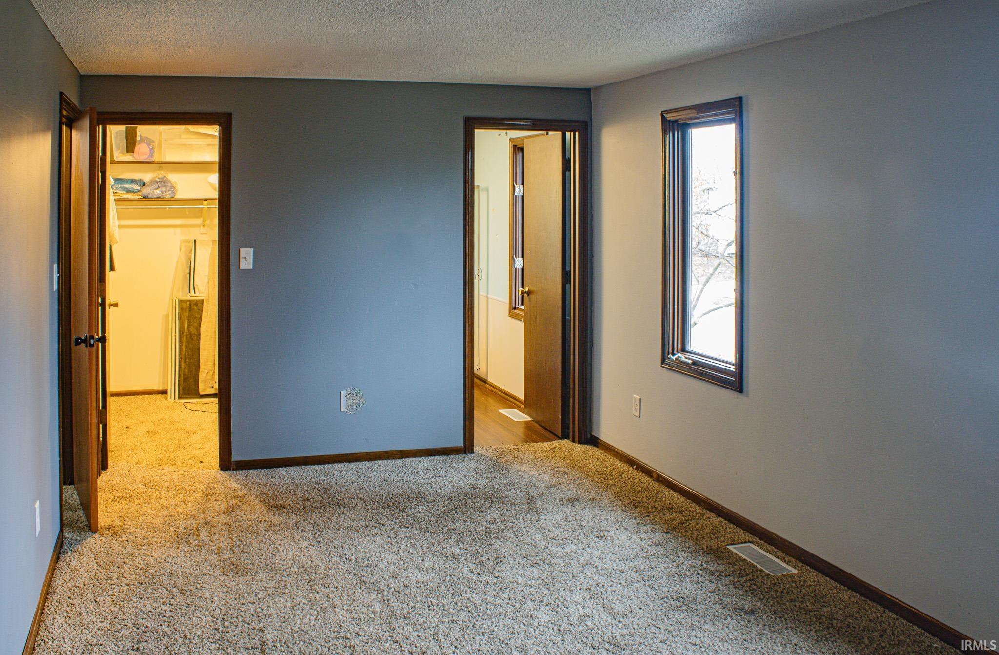 Unfurnished bedroom featuring a textured ceiling and light carpet