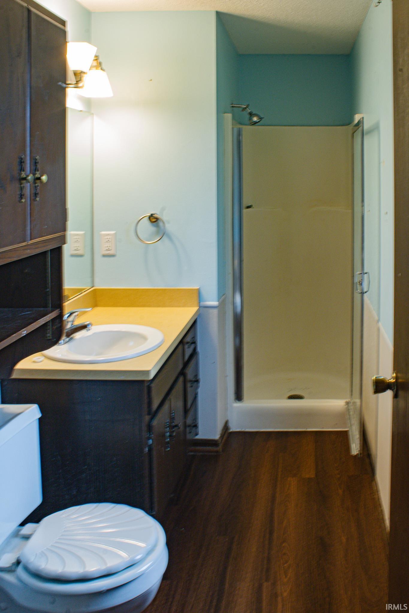 Full bathroom with a shower stall, vanity, dark wood-style floors, and a textured ceiling