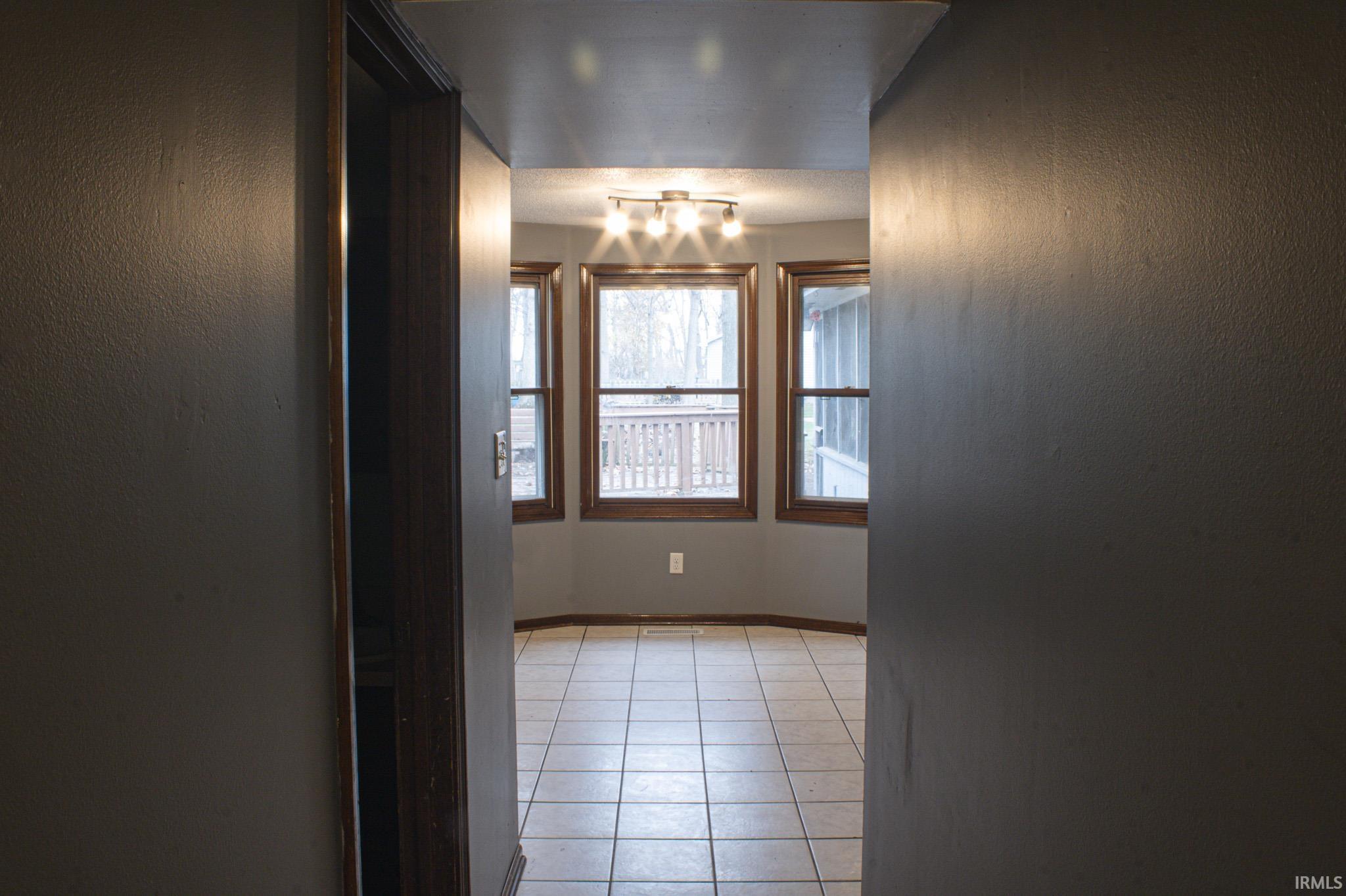 Empty room featuring light tile patterned floors and a textured wall