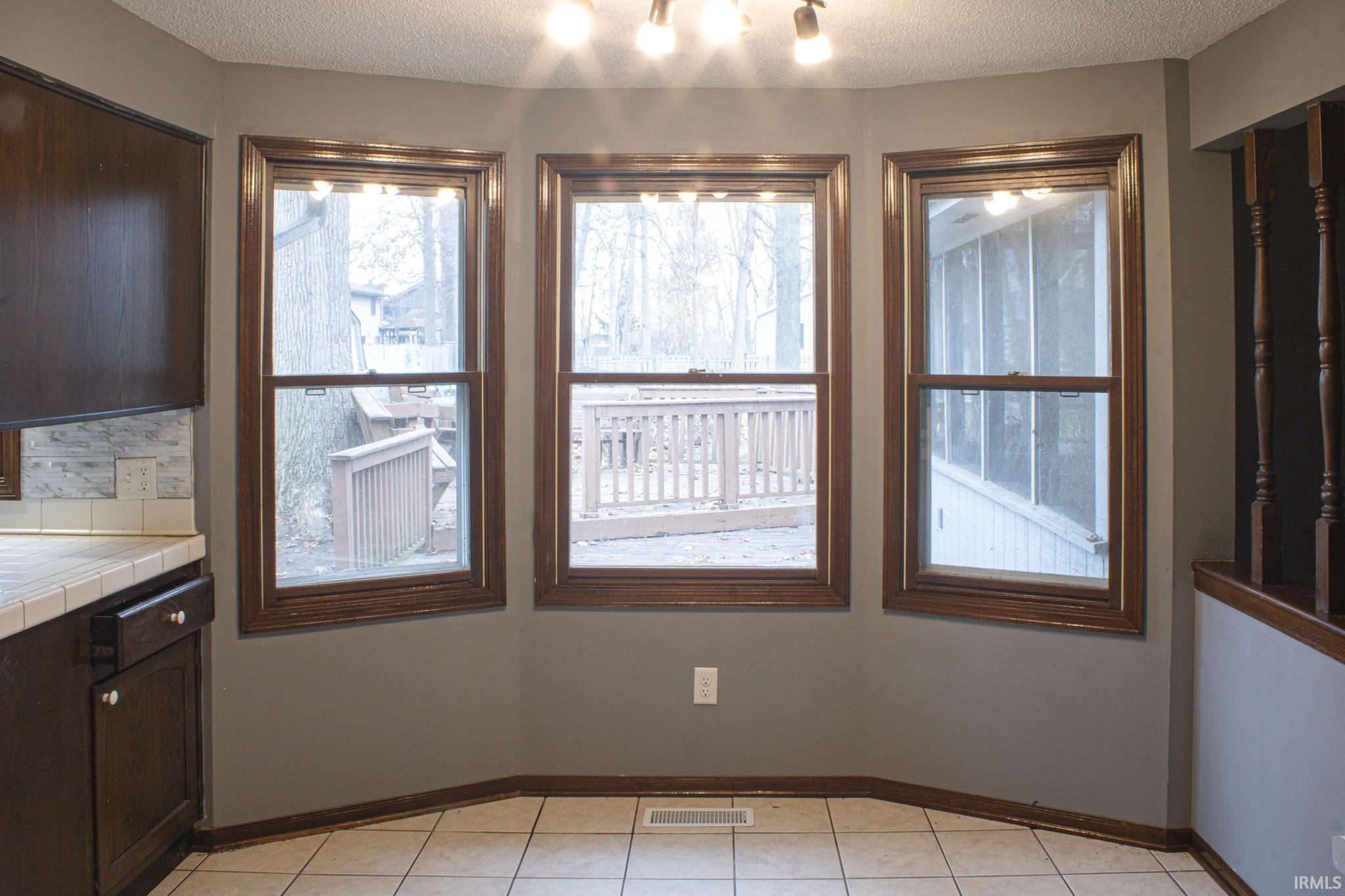 Unfurnished dining area featuring a textured ceiling and light tile patterned floors