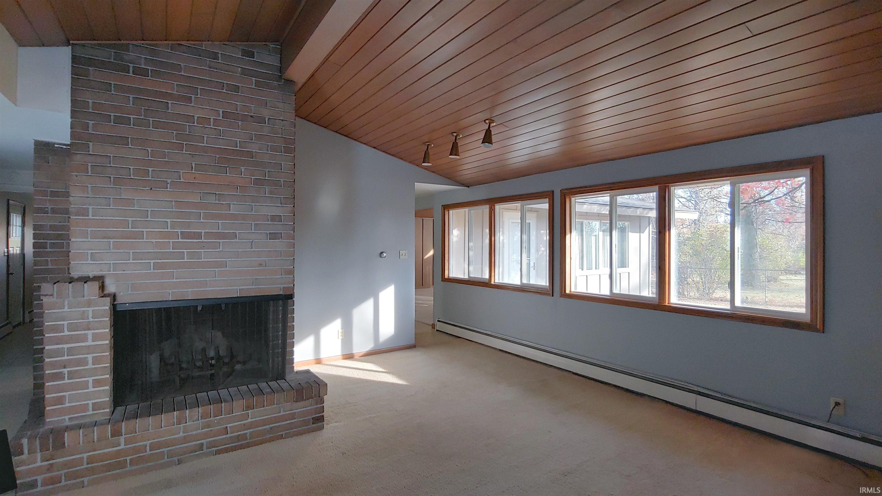 Living room featuring vaulted ceiling, fireplace, and MCM wood wall and ceiling
