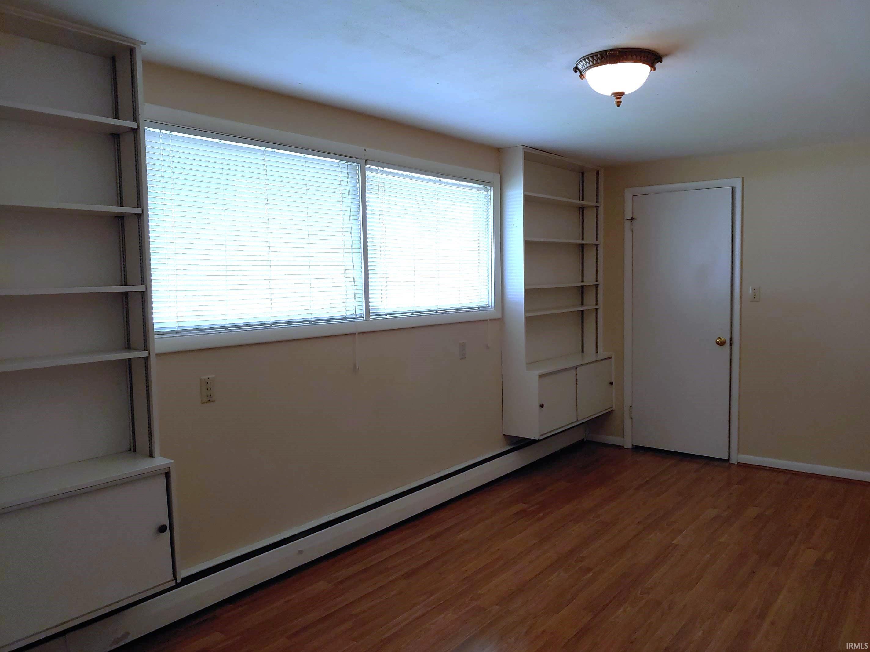 Unfurnished bedroom with a baseboard radiator and light wood-style floors
