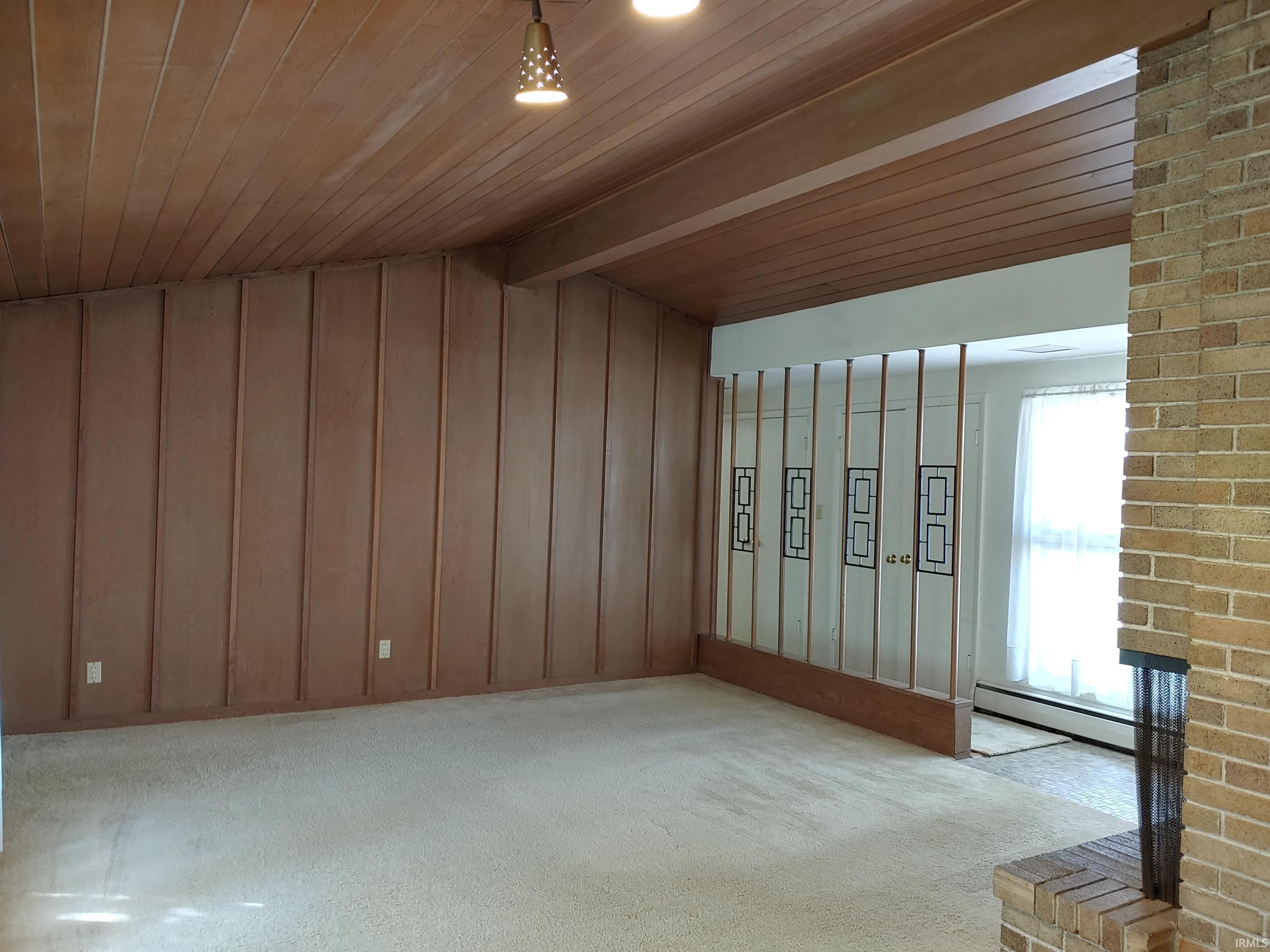 Living room featuring vaulted ceiling, and MCM wood wall and ceiling