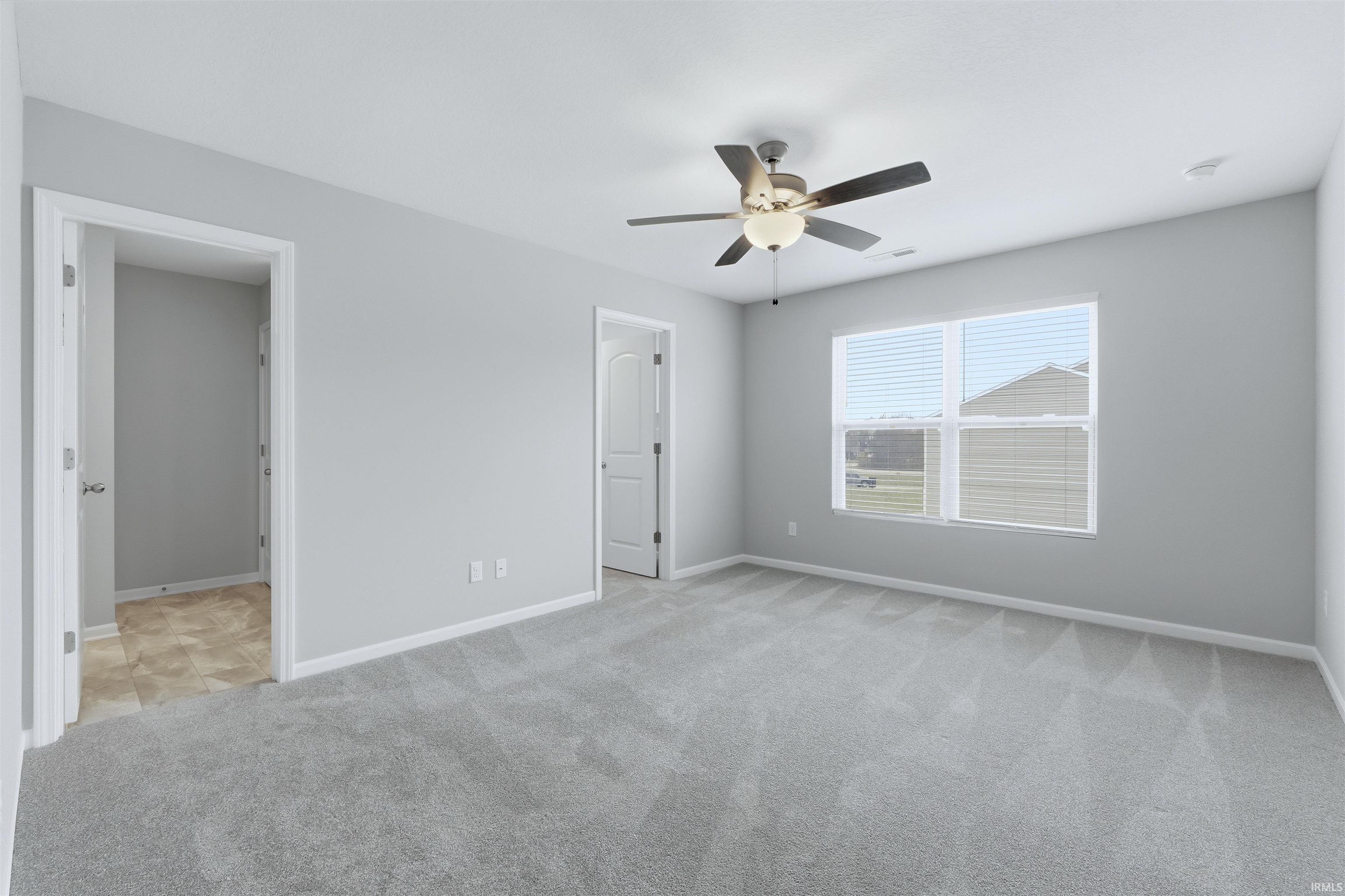 Owner Suite Bedroom with light carpet and a ceiling fan