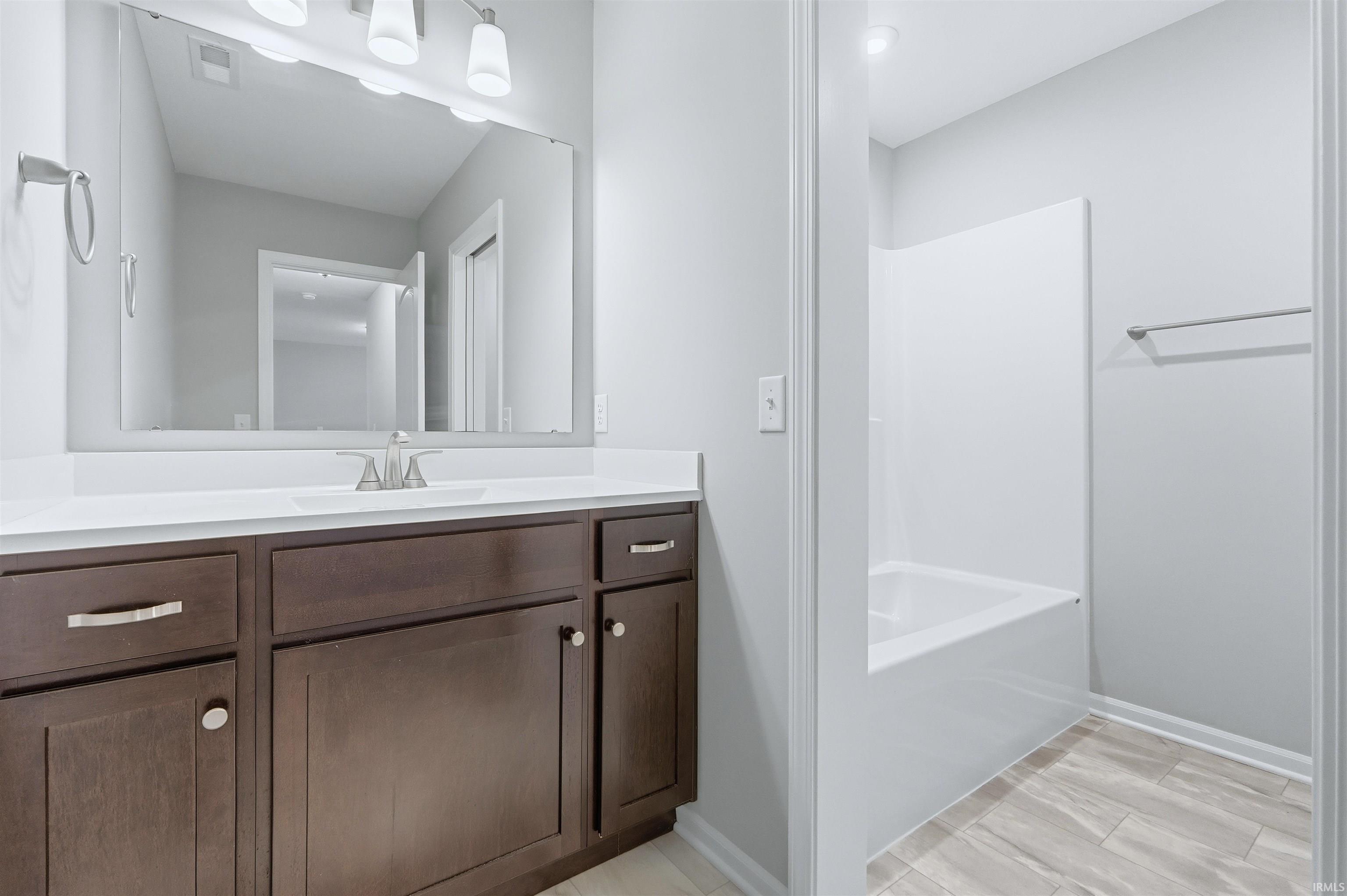 Full bathroom with vanity, shower and tub combination, and light wood-style floors