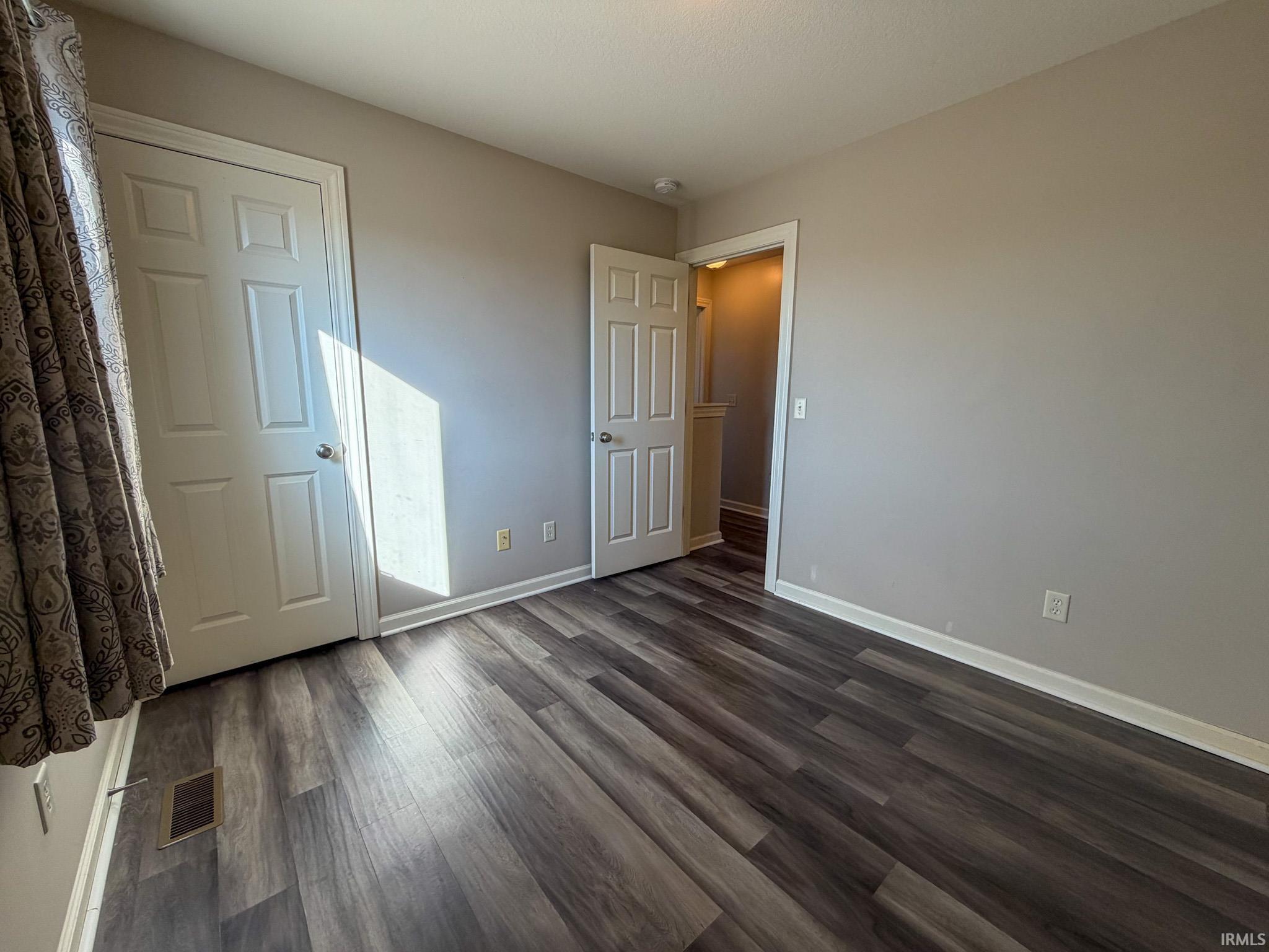 Unfurnished bedroom with dark wood finished floors and baseboards