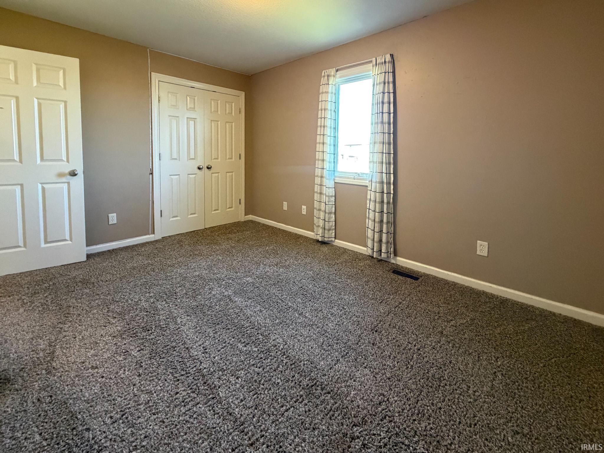Unfurnished bedroom featuring a closet and dark colored carpet