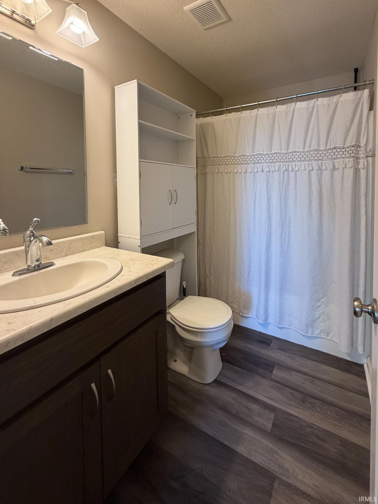 Bathroom with a shower with curtain, a textured ceiling, vanity, and dark wood-style floors