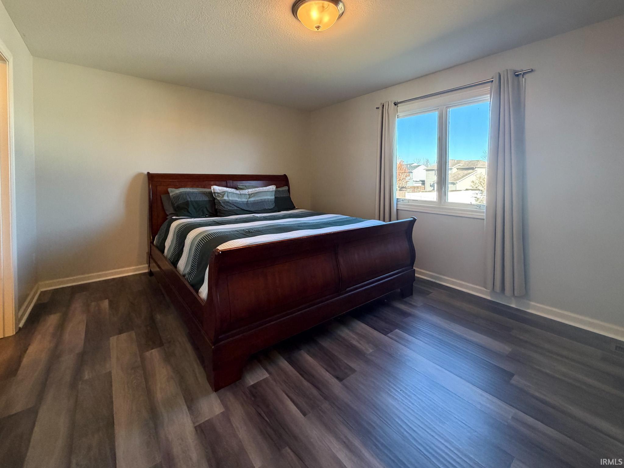 Bedroom with baseboards and dark wood-style flooring