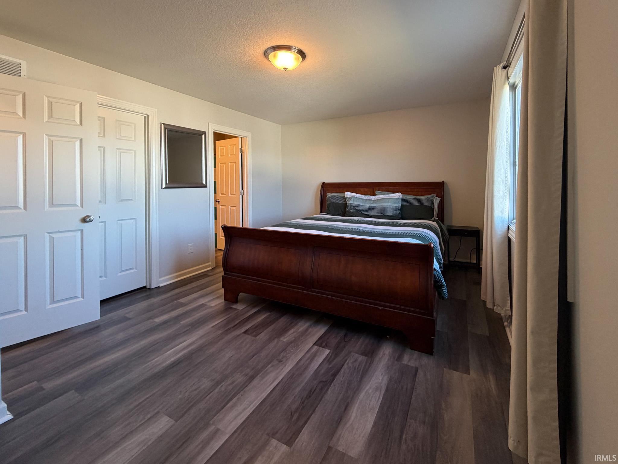 Bedroom with dark wood-type flooring and baseboards