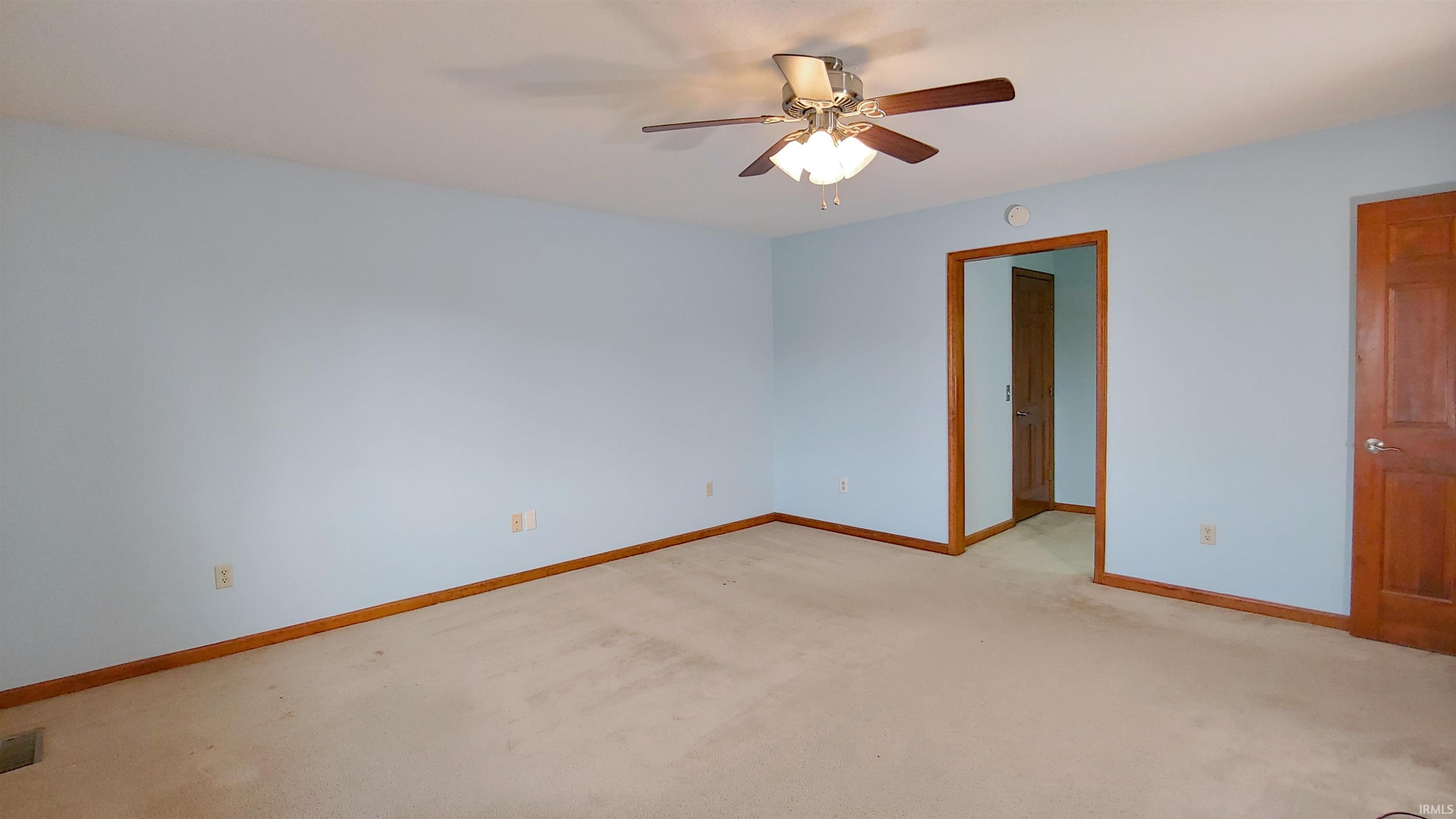 Primary bedroom featuring a ceiling fan, full bath and walk-in closet