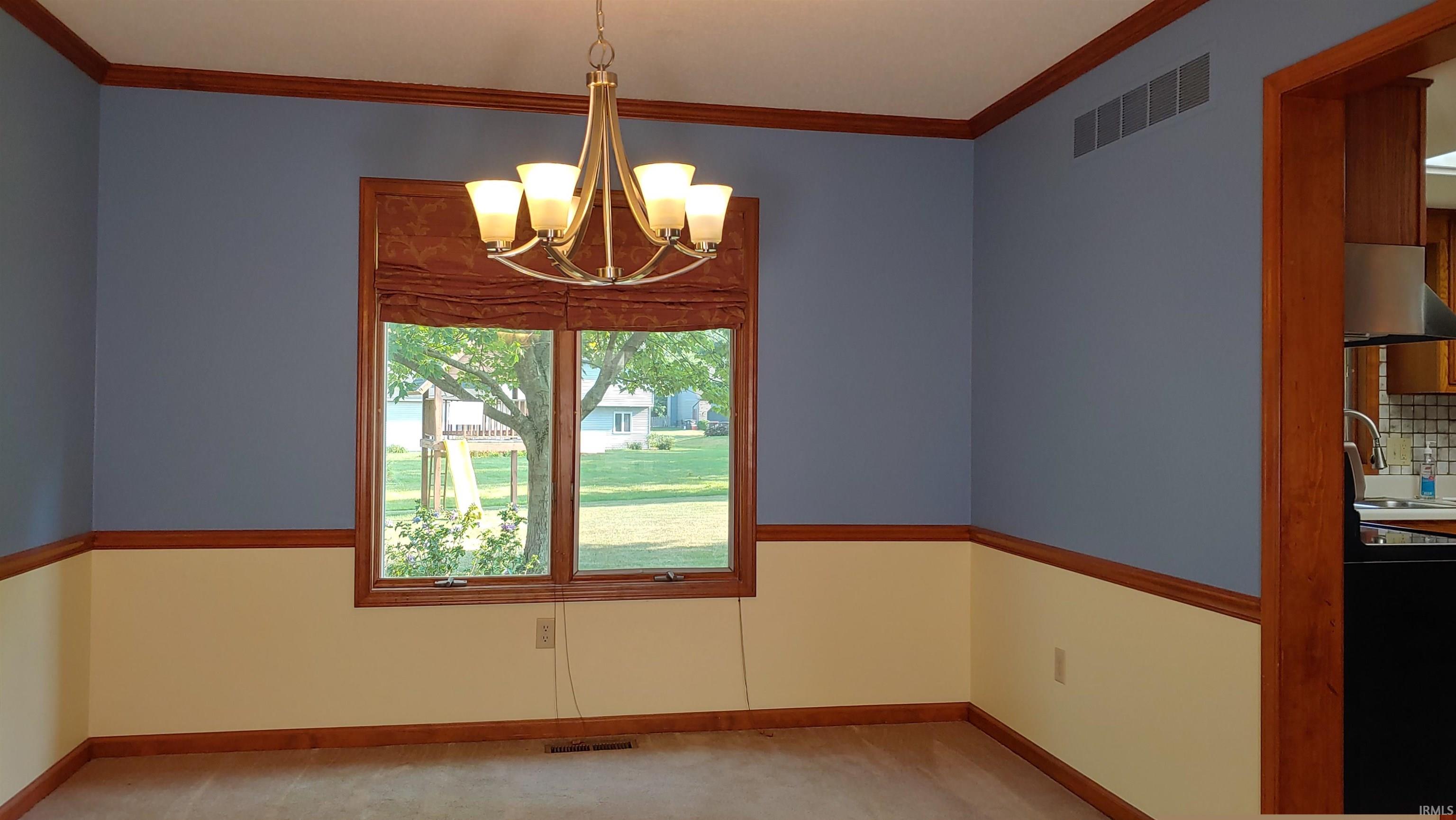 Diningroom with a chandelier, crown molding, and carpet