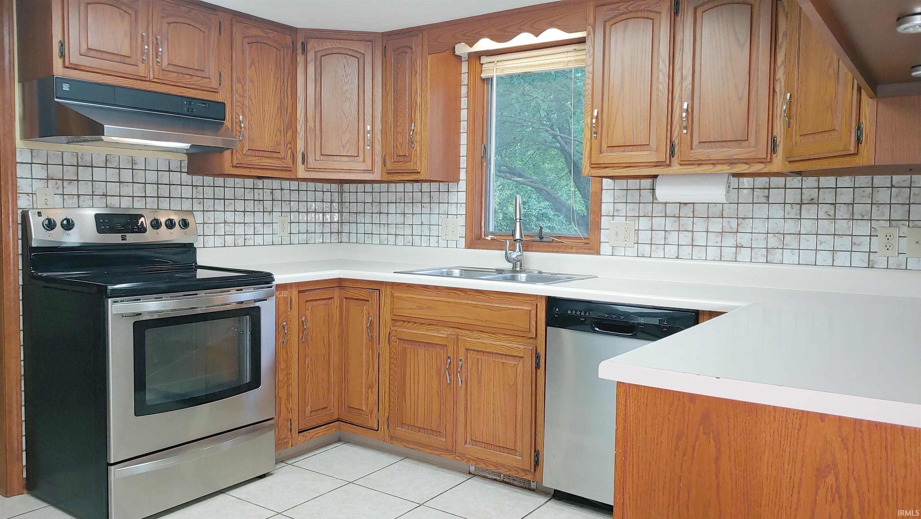 Kitchen featuring stainless steel appliances, natural wood cabinets, under cabinet range hood