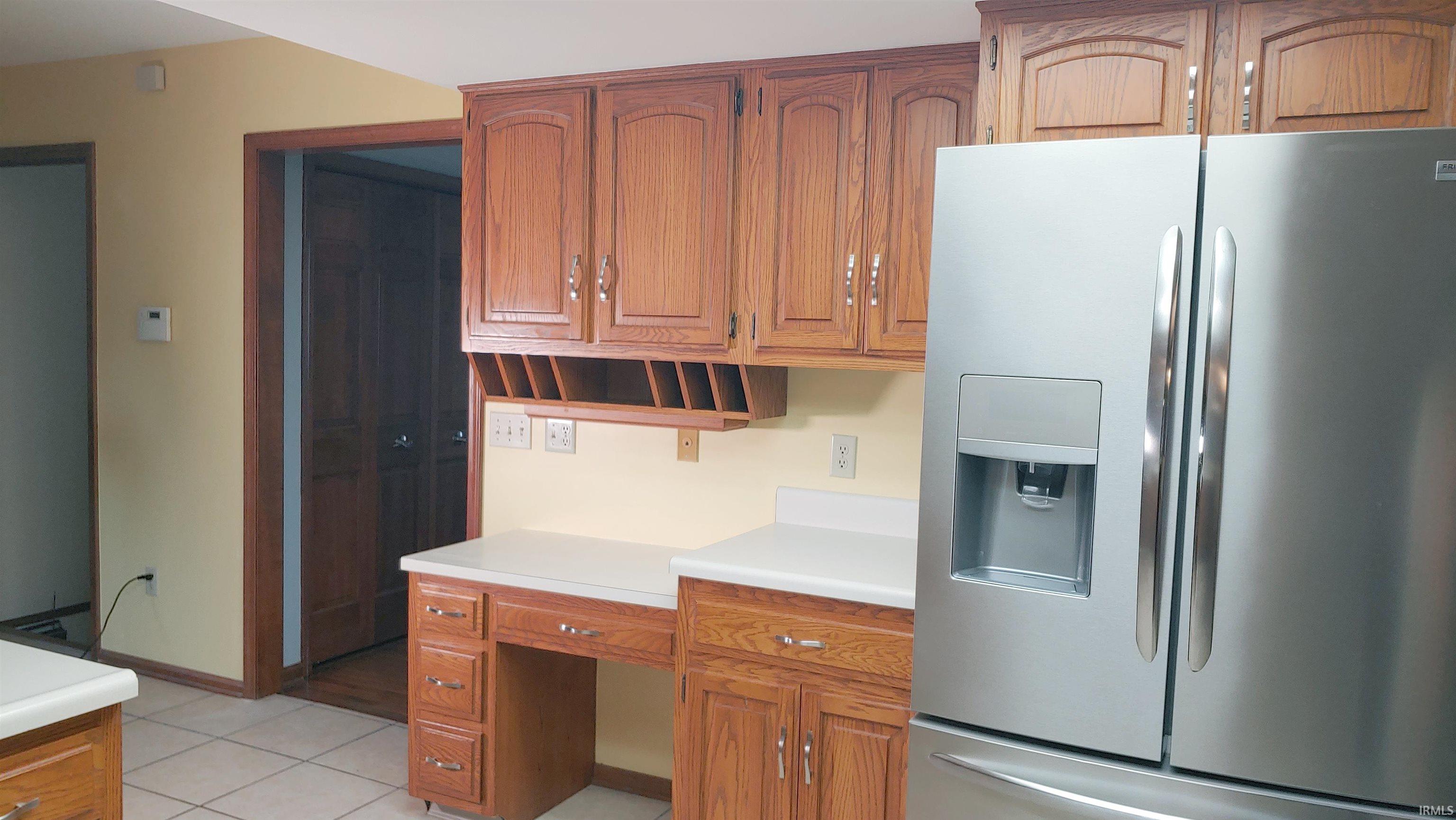 Kitchen featuring stainless steel fridge, natural wood cabinets and writing desk
