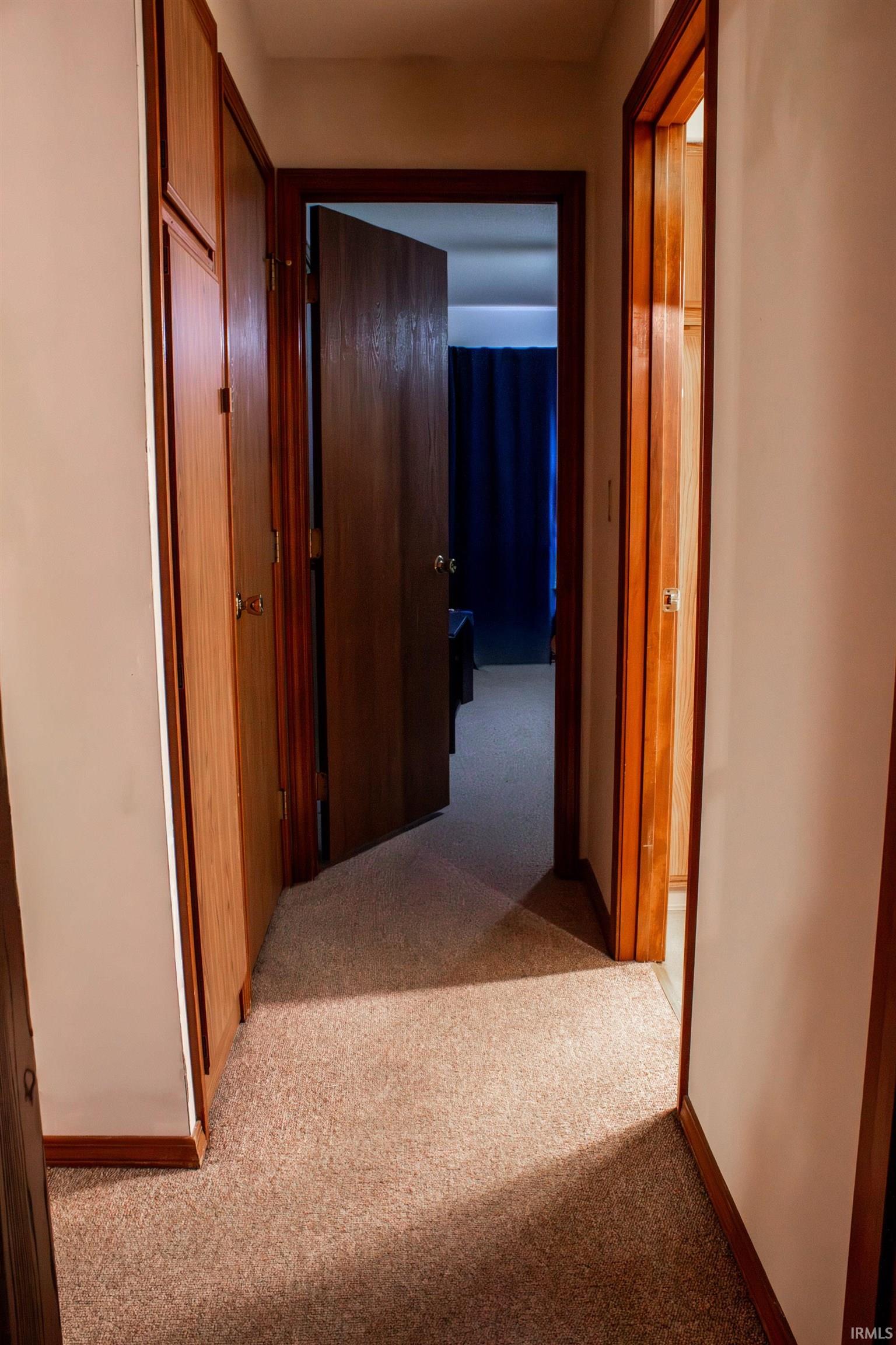 Corridor featuring light carpet and baseboards