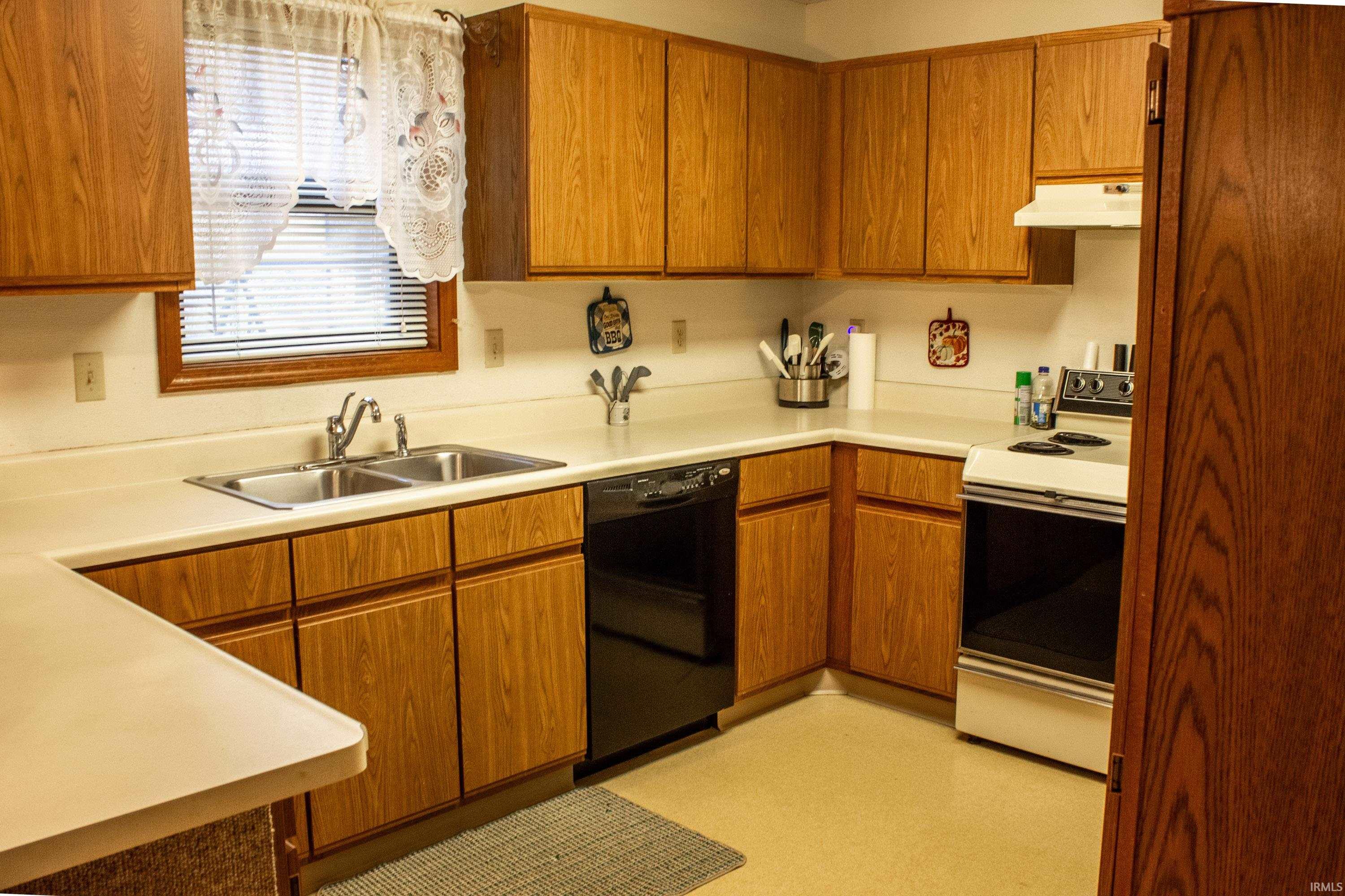 Kitchen with electric range, brown cabinetry, dishwasher, and light countertops