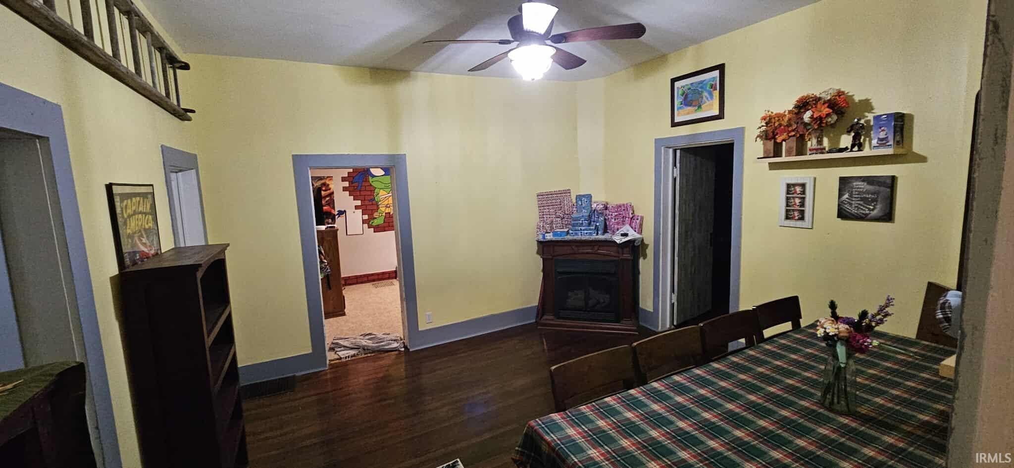 Bedroom with dark wood-style flooring, a fireplace, and a ceiling fan