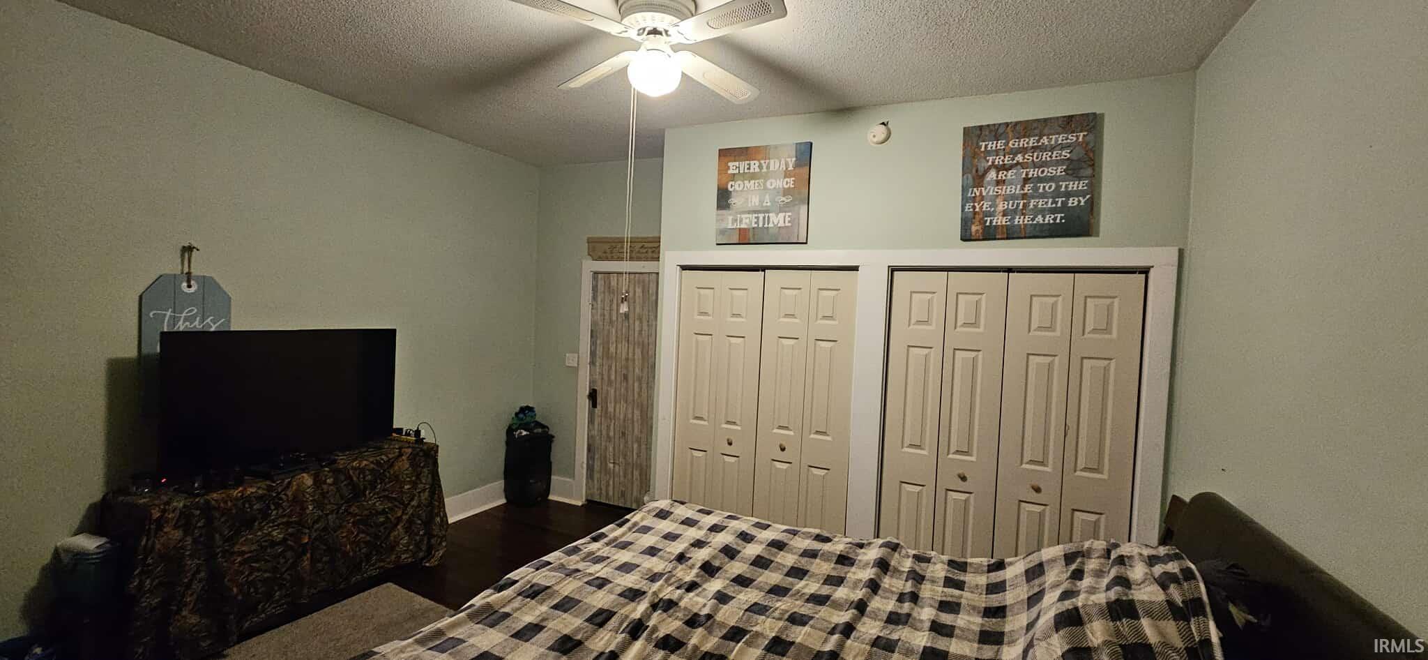 Bedroom with multiple closets, a textured ceiling, ceiling fan, and dark wood-style flooring