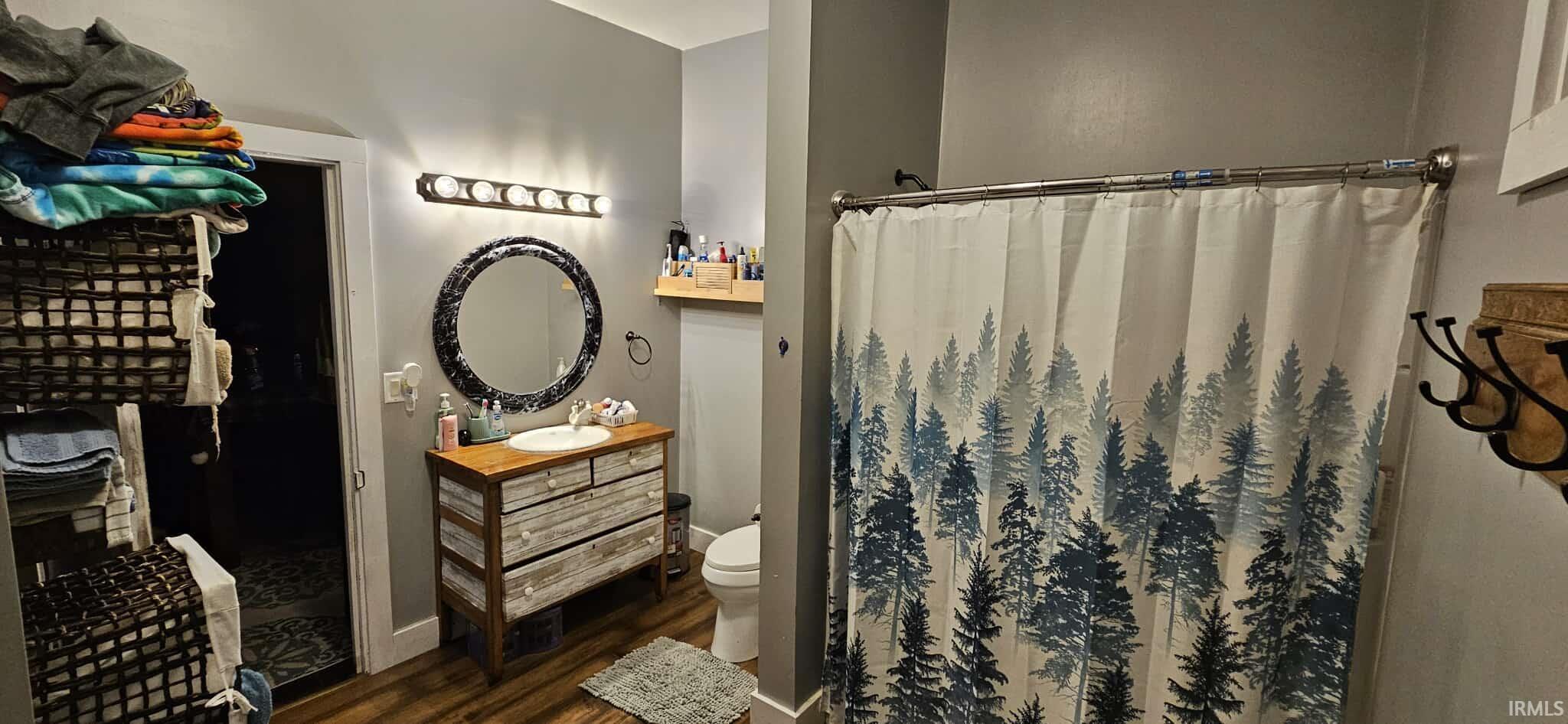 Full bath featuring vanity, a shower with curtain, and dark wood-style floors