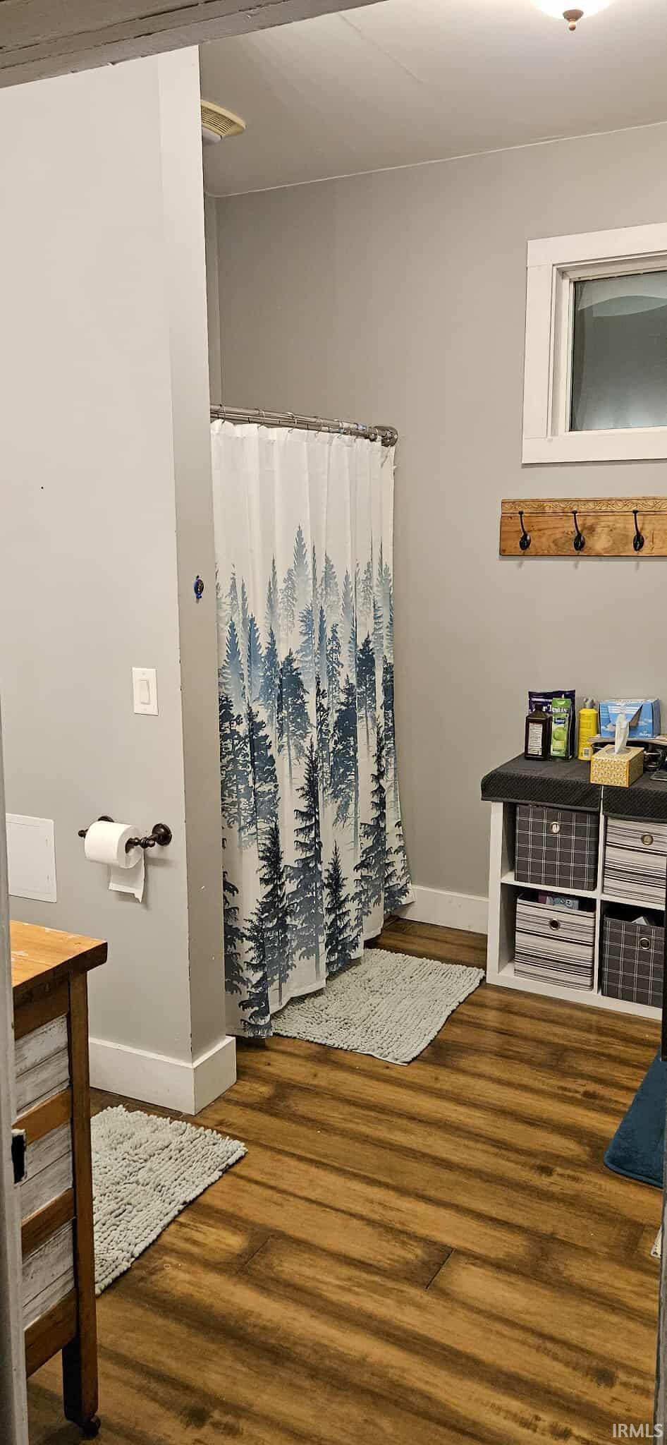 Bathroom featuring a shower with shower curtain and dark wood-style floors