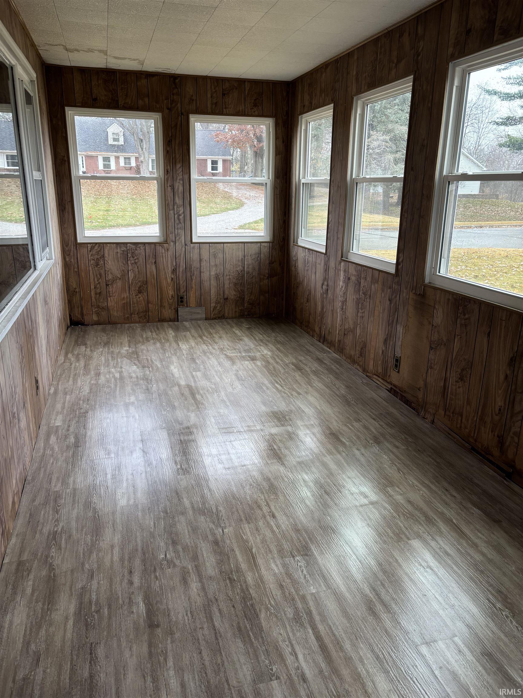 Unfurnished sunroom with wood walls and wood finished floors