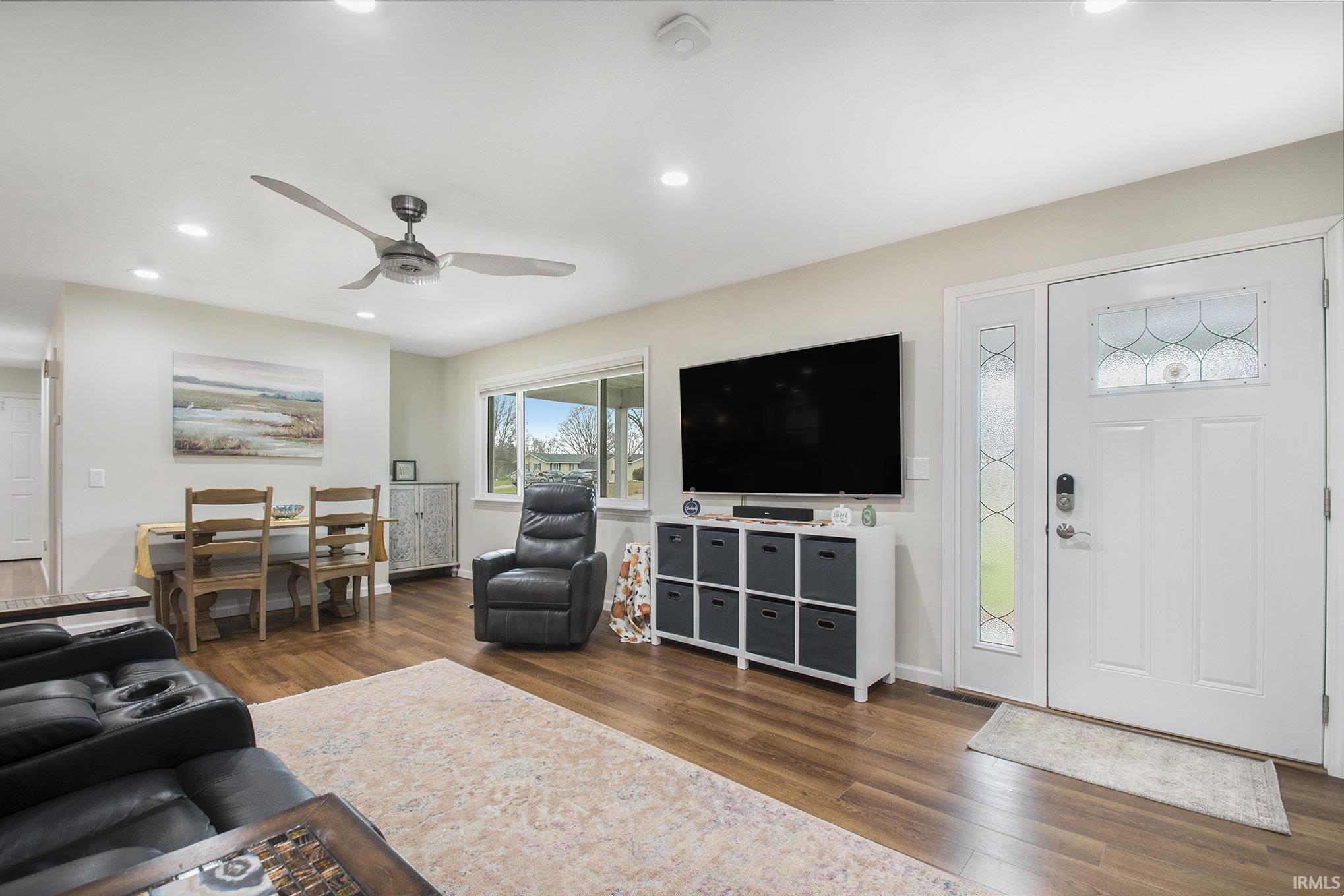 Living area featuring dark wood-type flooring, a ceiling fan, and recessed lighting
