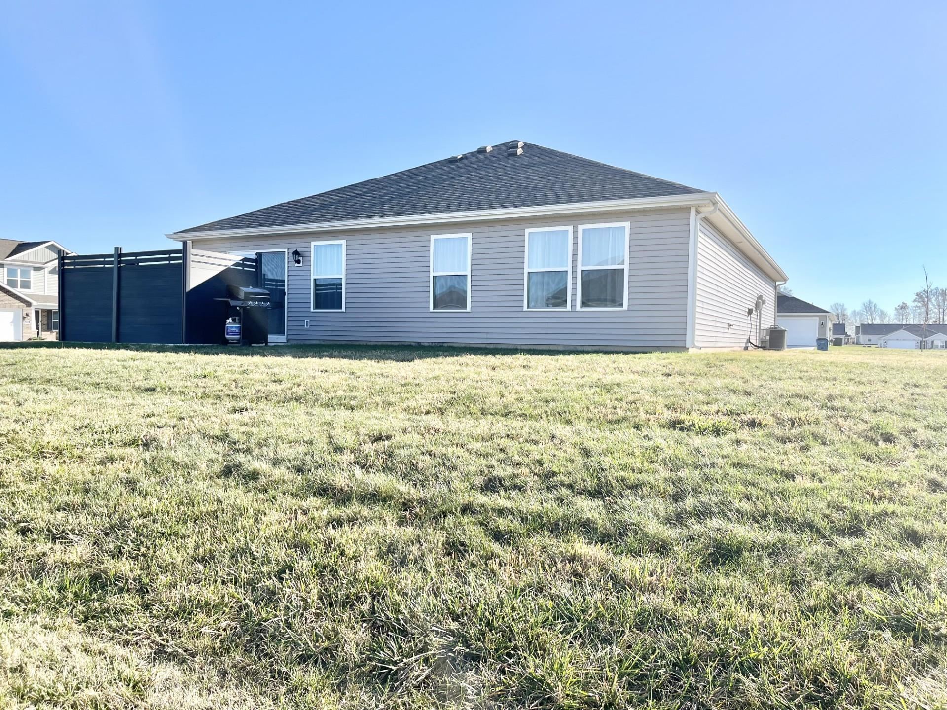 Rear view of property with a lawn and a shingled roof