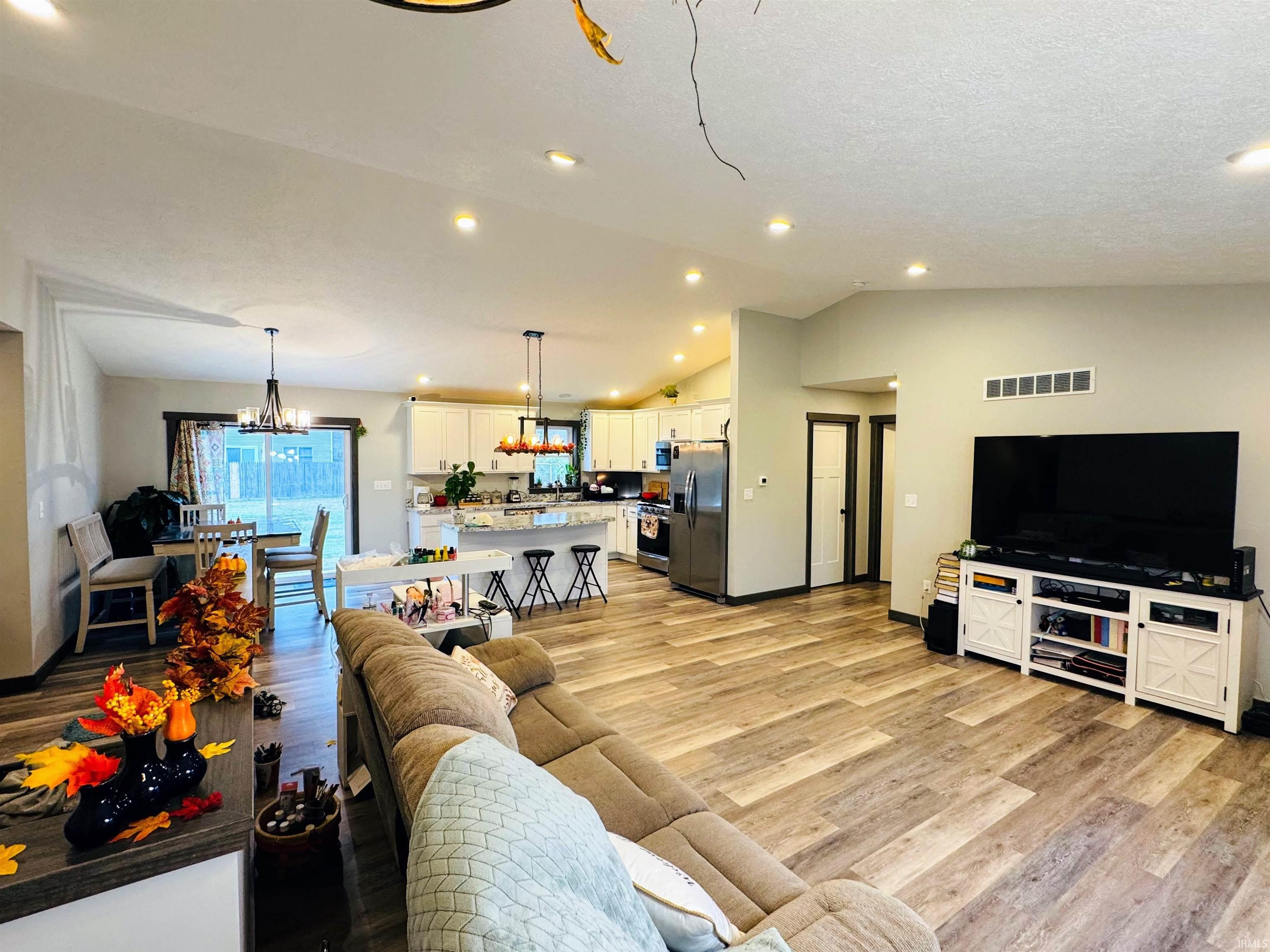 Living area featuring lofted ceiling, light wood-style flooring, a chandelier, and recessed lighting