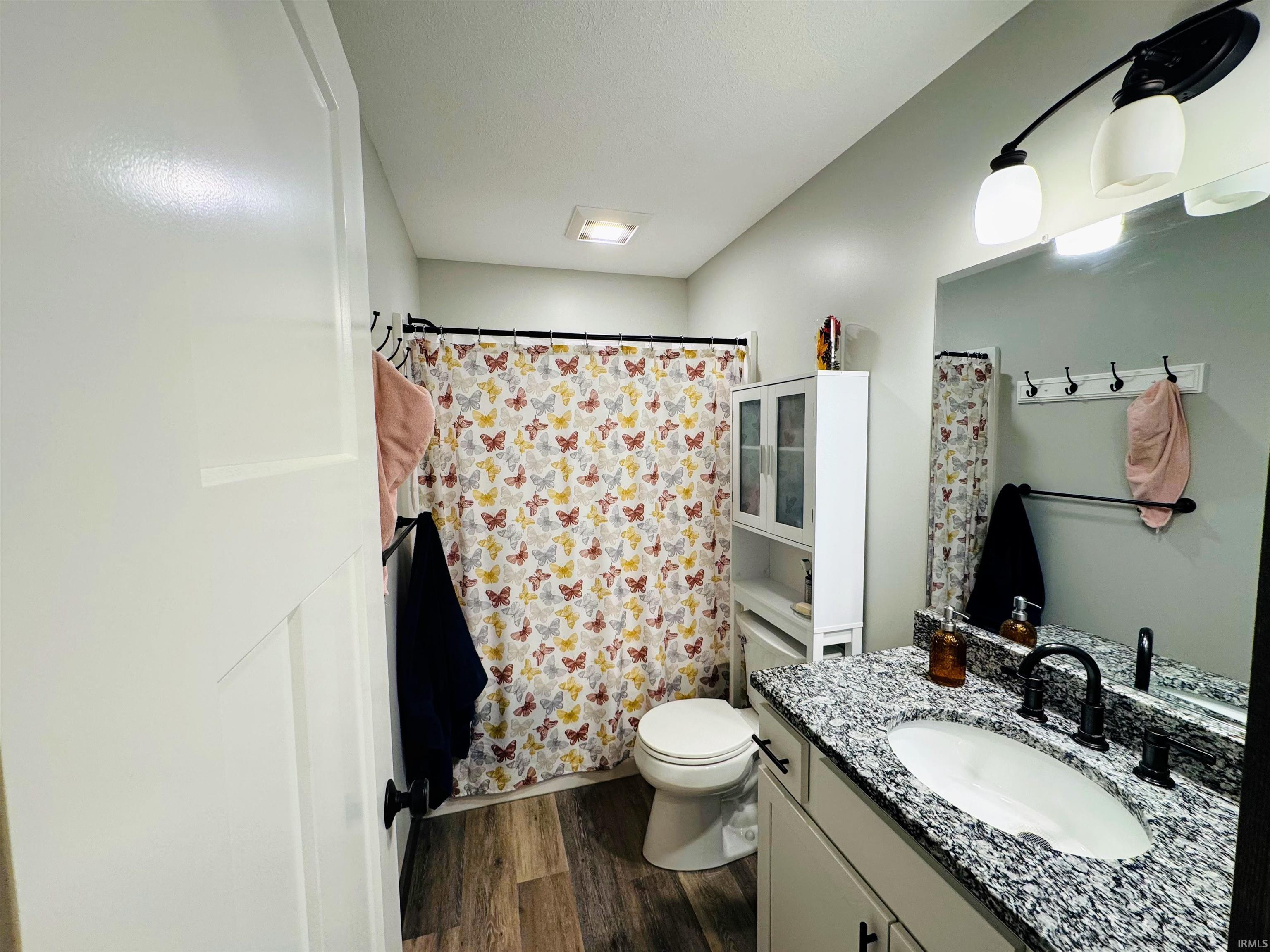 Bathroom featuring dark wood finished floors, vanity, and a shower with curtain