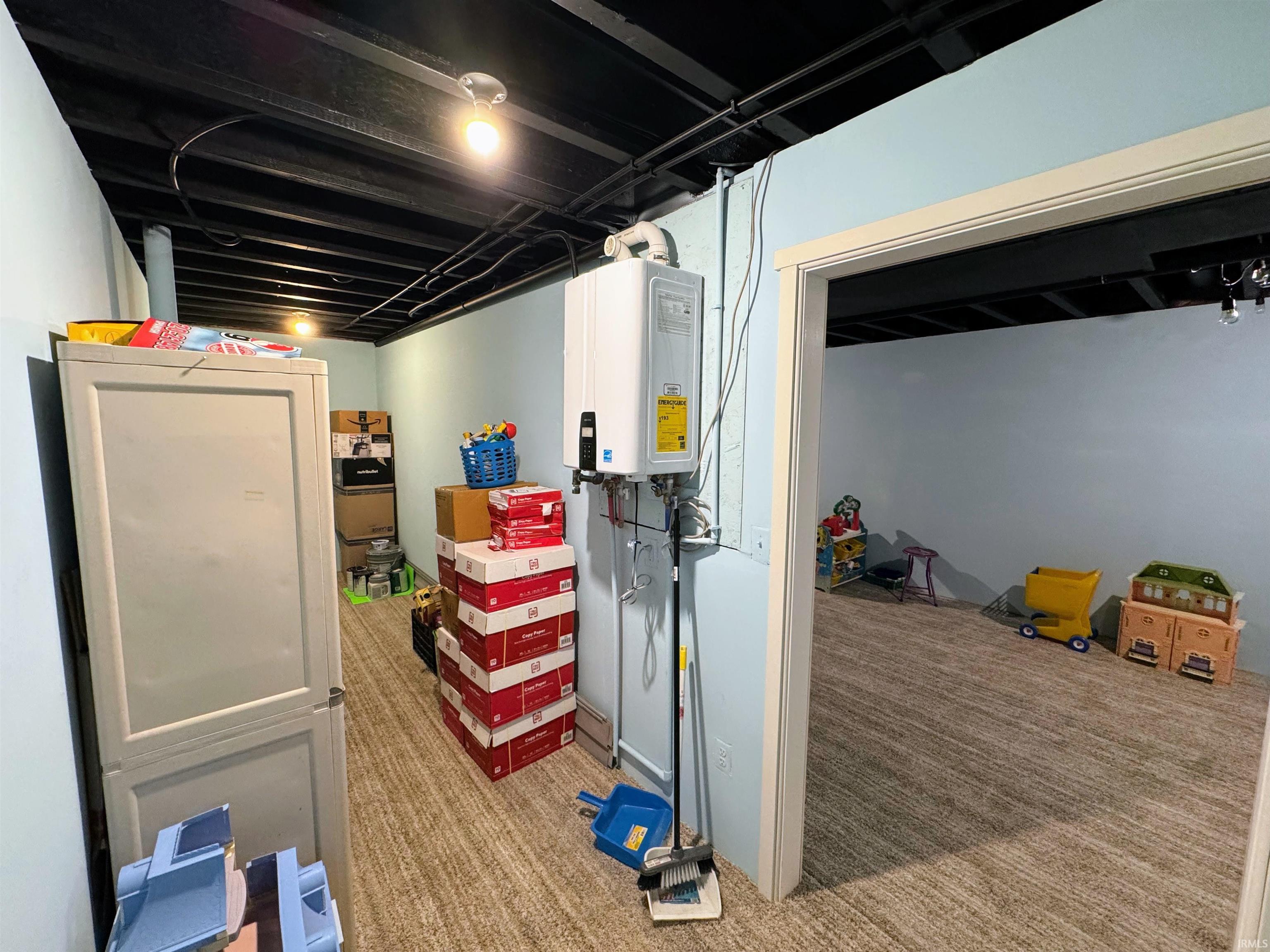 Finished below grade area featuring tankless water heater and light colored carpet