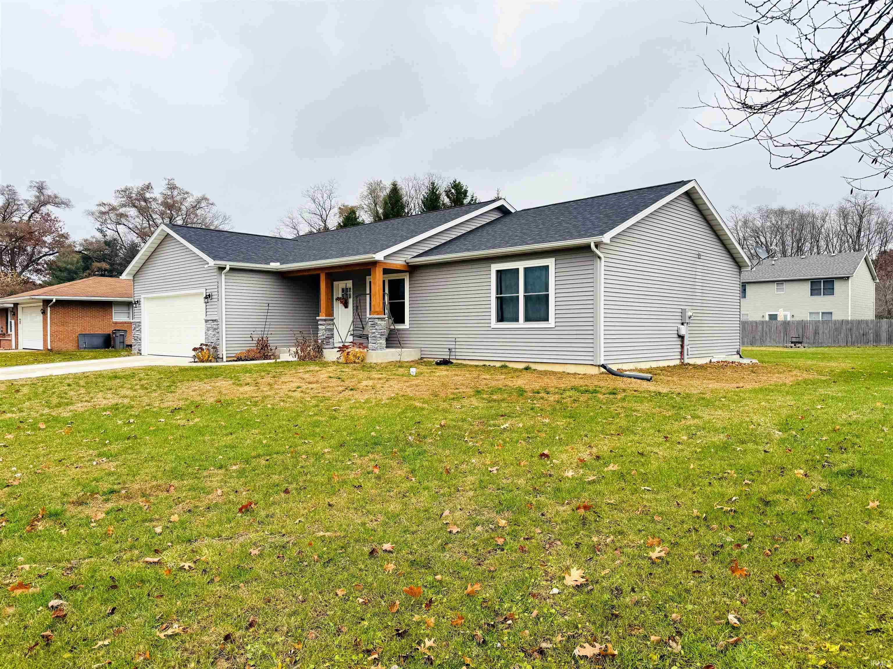 Ranch-style home featuring an attached garage, driveway, roof with shingles, and a porch