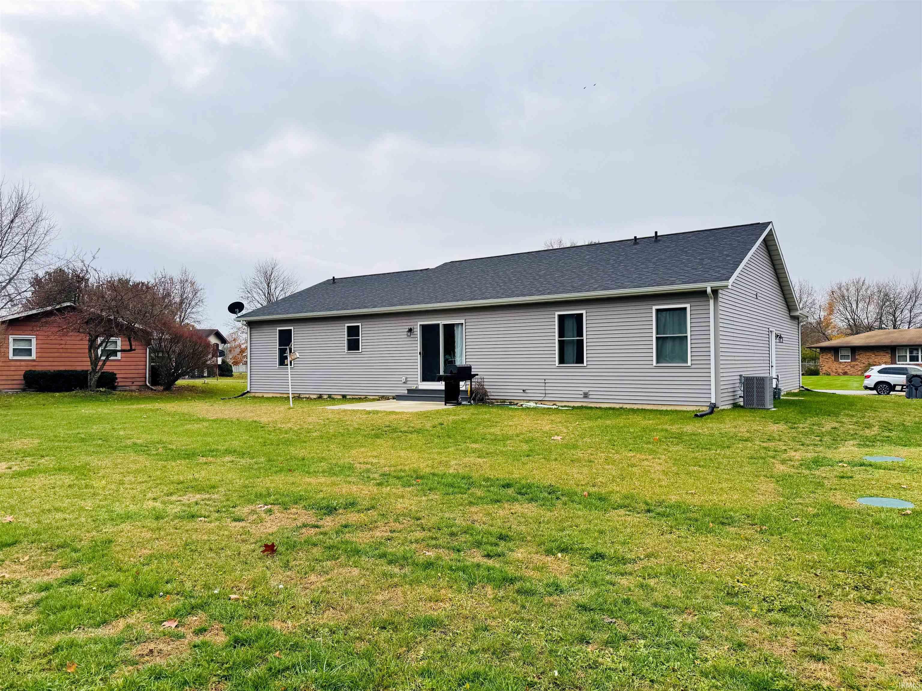 Rear view of property featuring a patio area, a lawn, and roof with shingles
