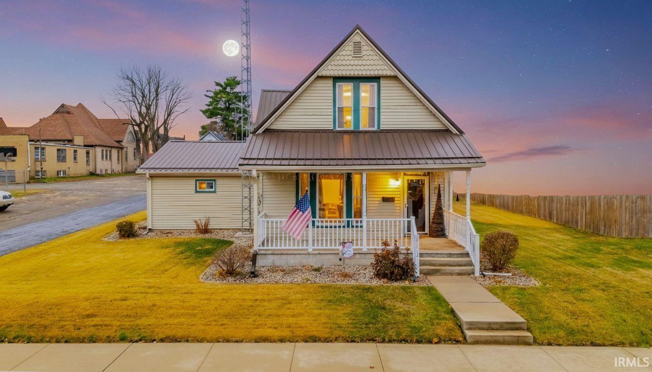 View of front of property with a front yard, a porch, a metal roof, and a standing seam roof