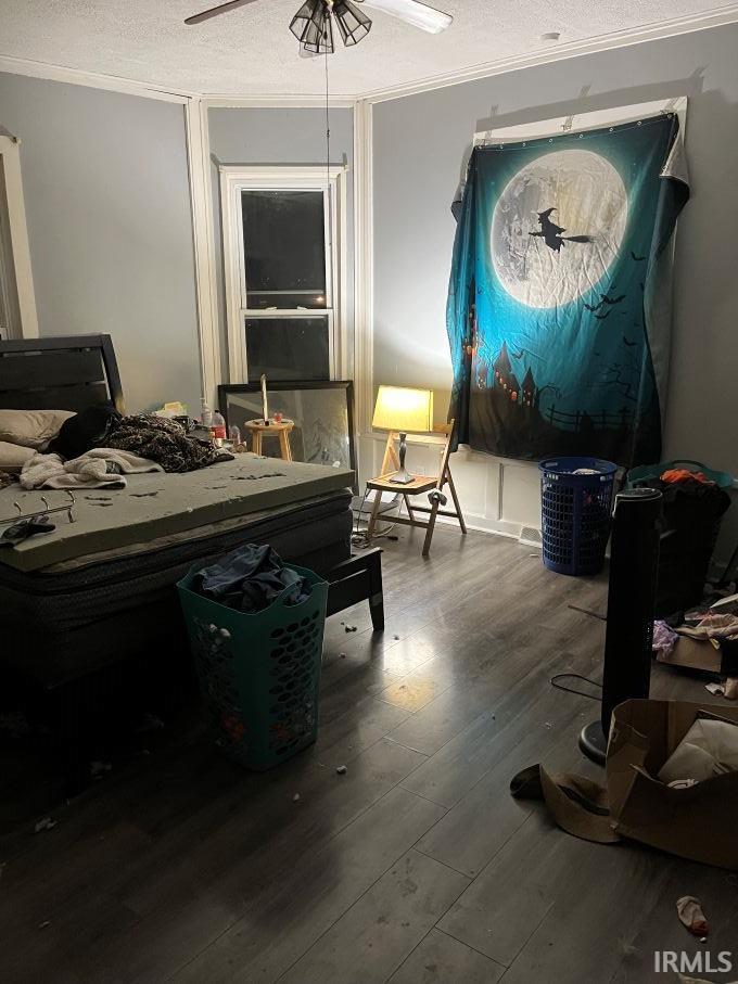 Bedroom featuring a textured ceiling, hardwood / wood-style floors, a ceiling fan, and ornamental molding