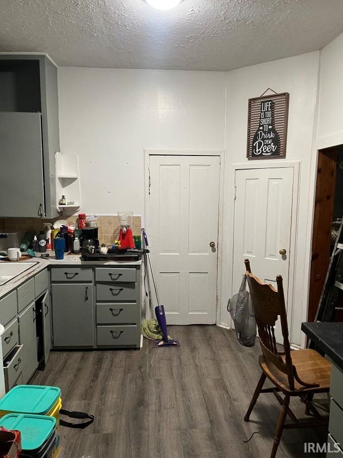 Kitchen featuring a textured ceiling, gray cabinets, dark wood finished floors, and light countertops