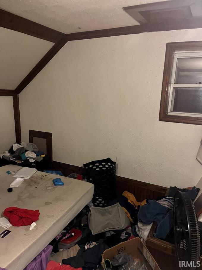 Bedroom with wainscoting, wood walls, and a textured wall